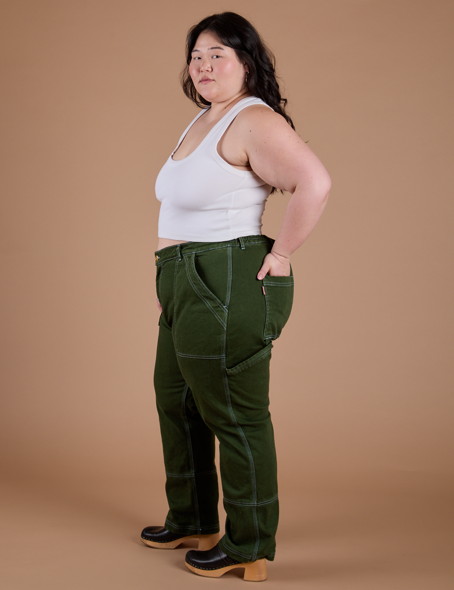 Side view of Carpenter Jeans in Evergreen and Cropped Tank in Vintage Tee White on Ashley
