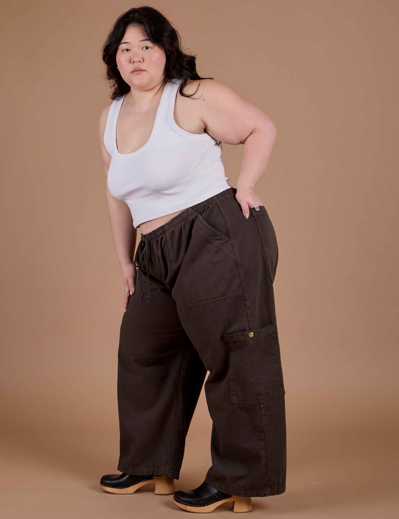 Angled front view of Drop Pocket Cargo Pants in Espresso Brown and Cropped Tank in vintage tee white on Ashley