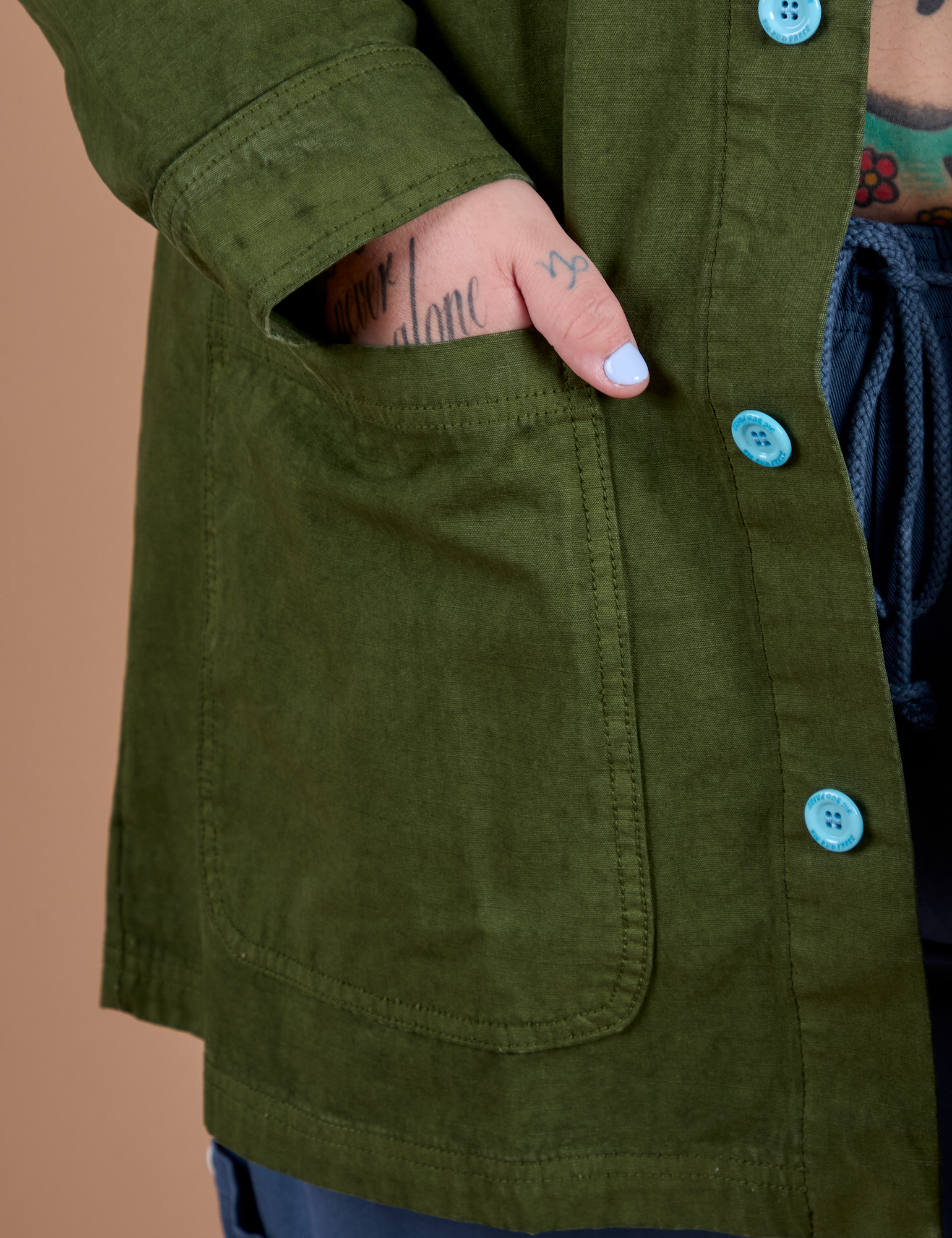 Close up of Sam's hand in the front pocket of Ripstop Field Coat in Evergreen