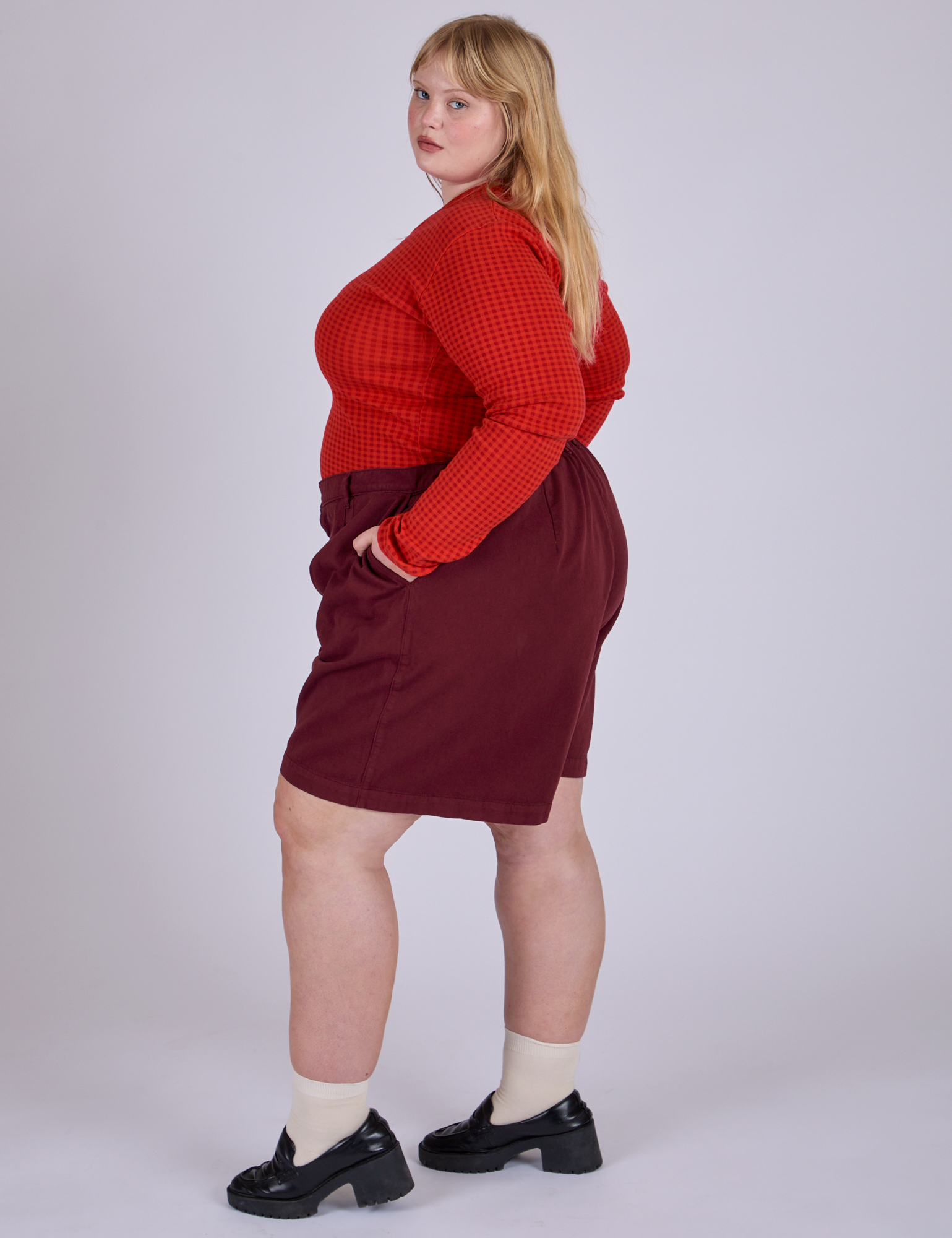 Side view of Pleated Trouser Shorts in Red Wine and Long Sleeve Gingham Baby Tee in Mustang Red