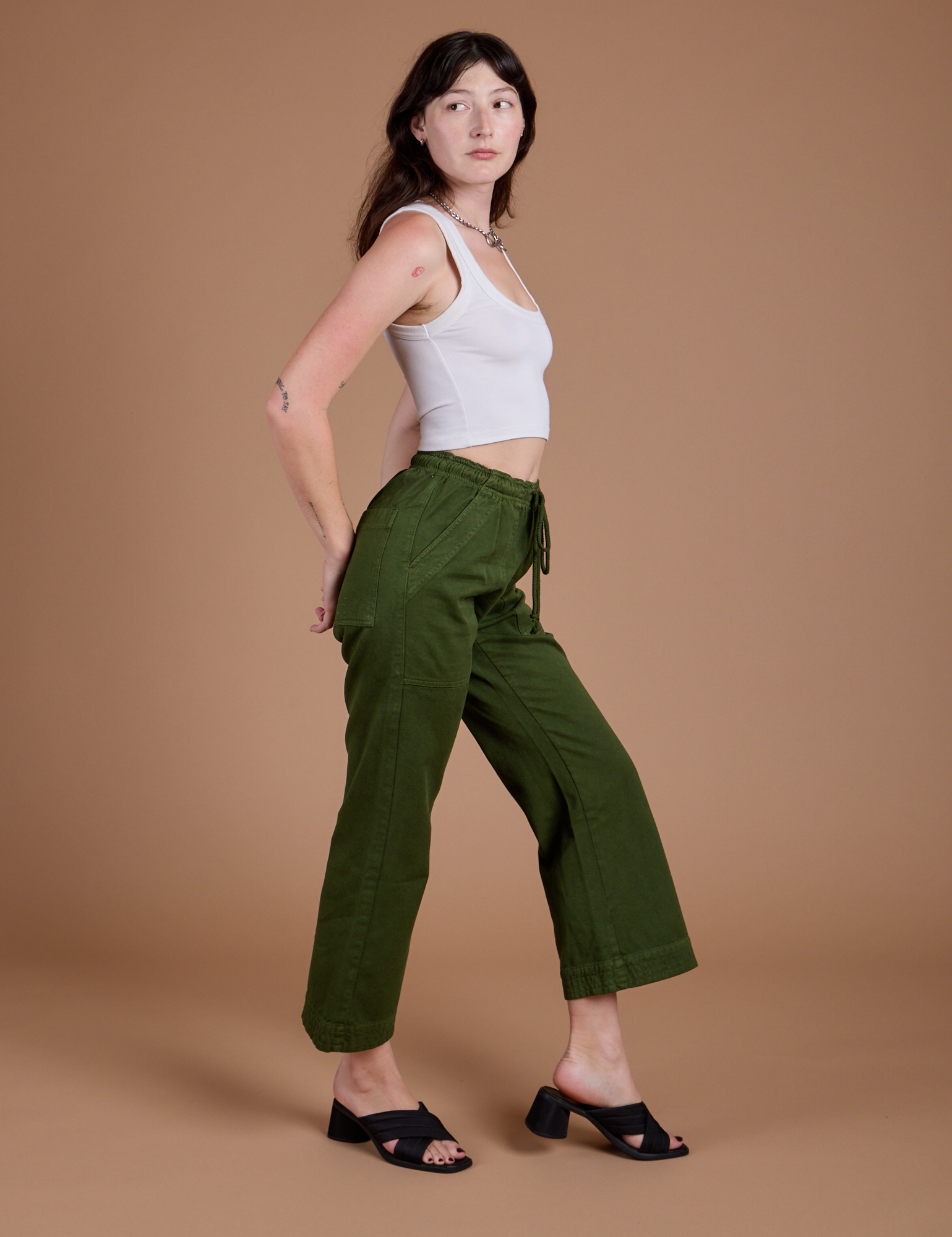 Side view of Organic Action Pants in Evergreen and vintage tee white Cropped Tank on Alex