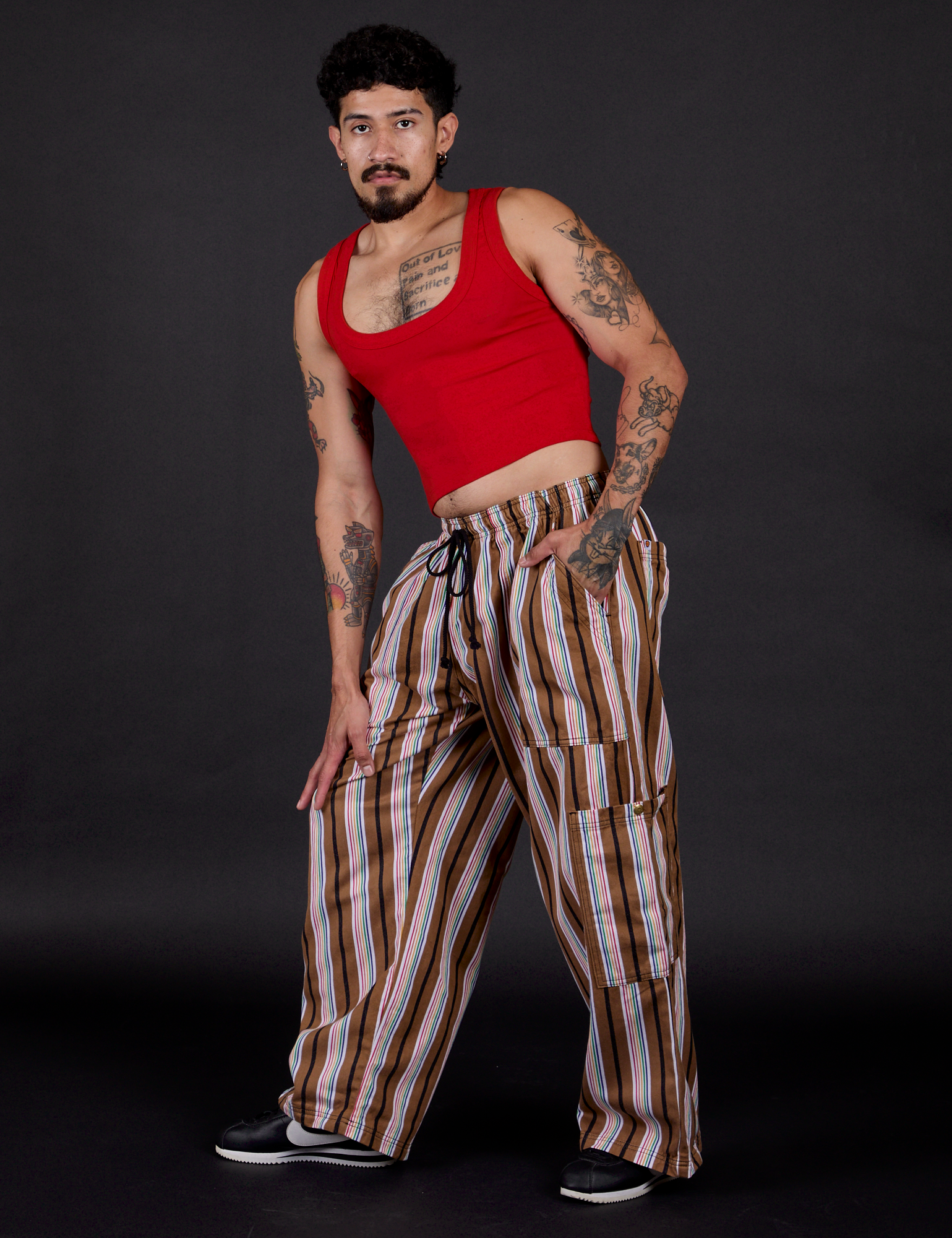Angled front view of  Striped Drop Pocket Pants in Retro Rainbow and mustang red Cropped Tank on Jesse