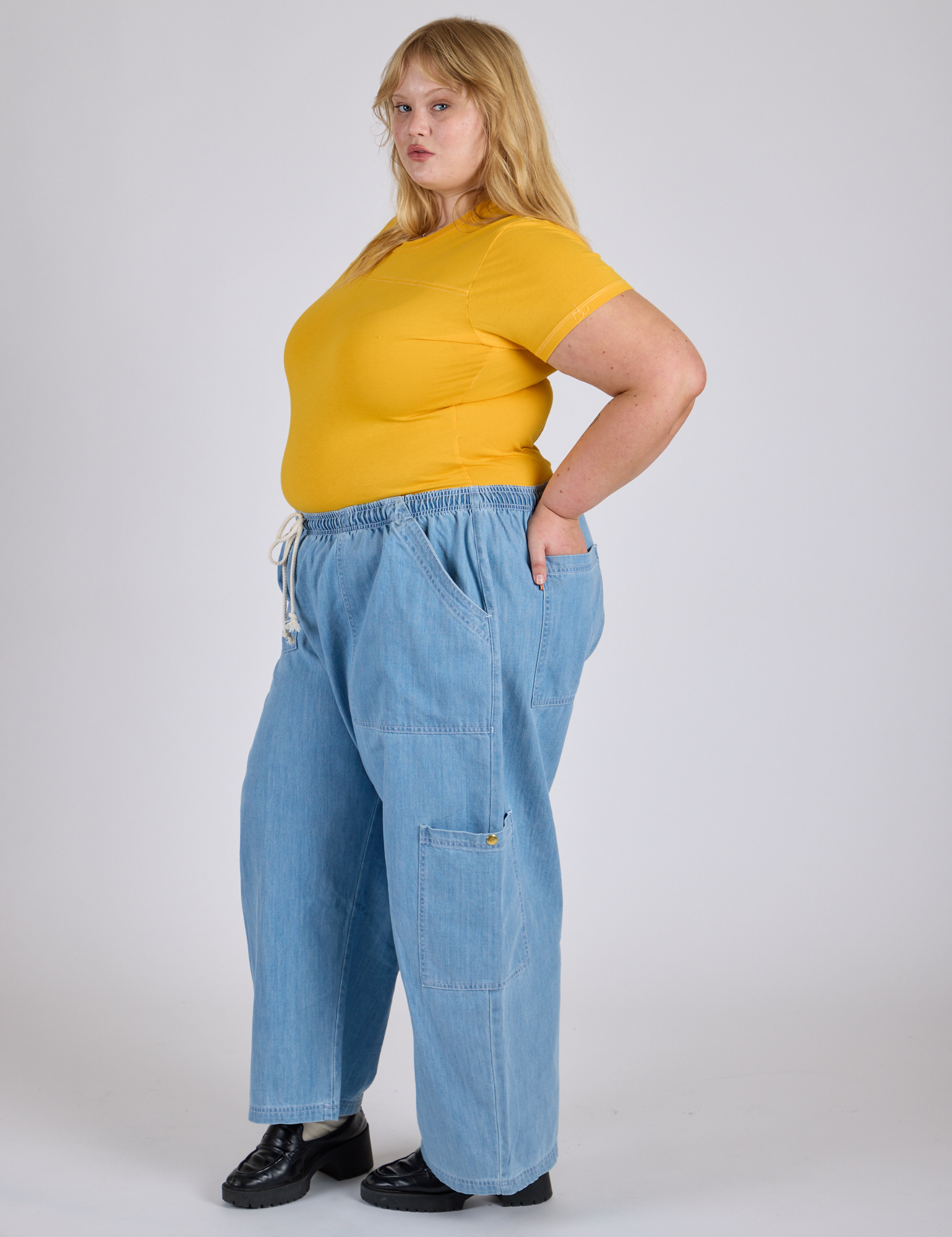 Side view of Jr. Varsity Tee in Sunshine Yellow tucked into light wash Denim Drop Pocket Pants