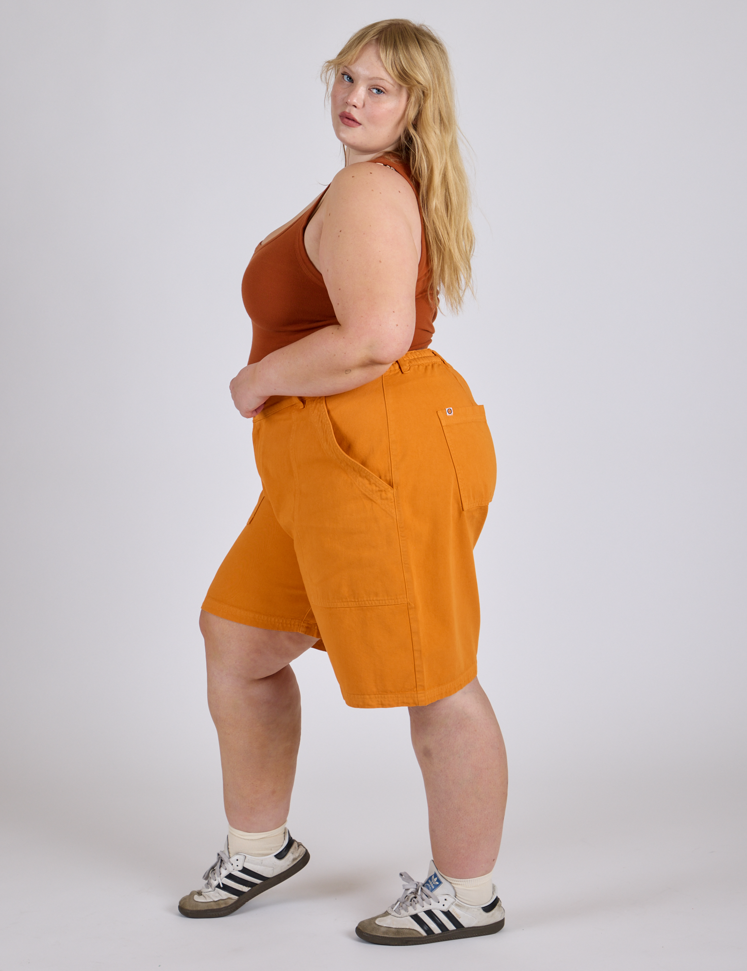 Side view of Longline Work Shorts in Creamsicle Orange and burnt terracotta Cropped Tank on Juliet