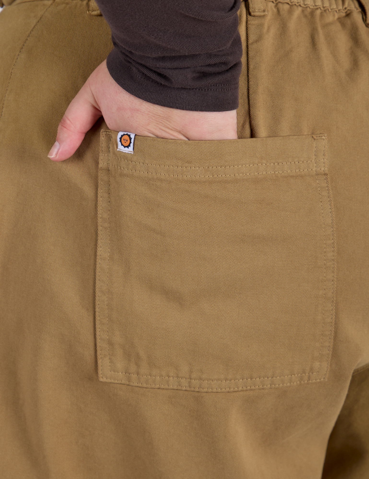 Close up of Juliet's hand in the back pocket of Longline Work Shorts in Desert Brown