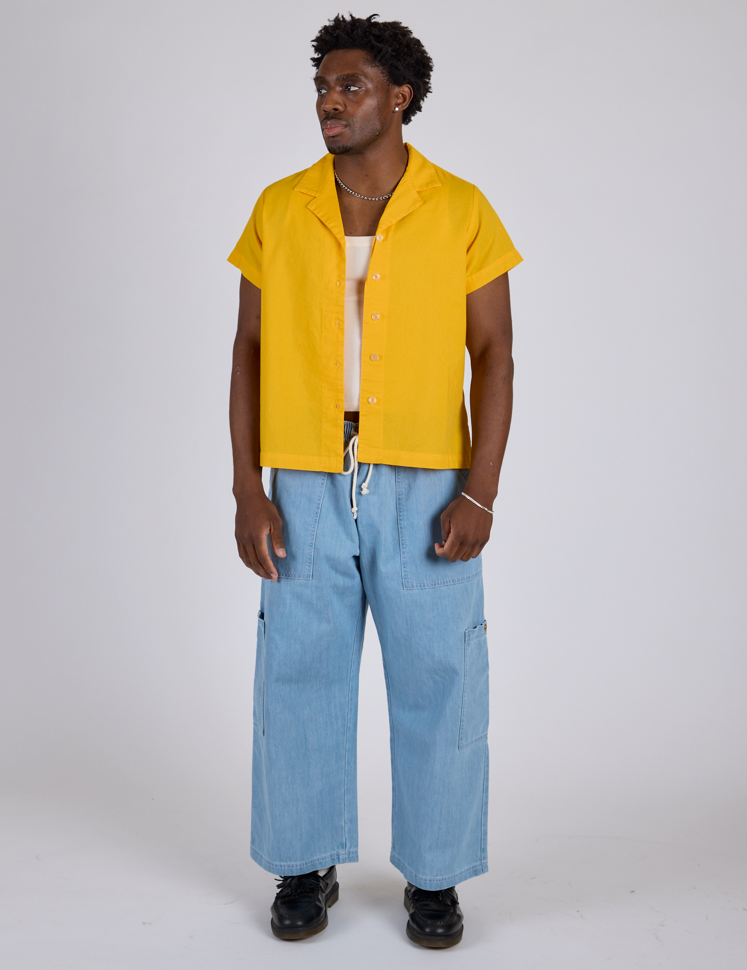 Isaac is wearing Pantry Button-Up in Sunshine Yellow and light wash Denim Drop Pocket Pants