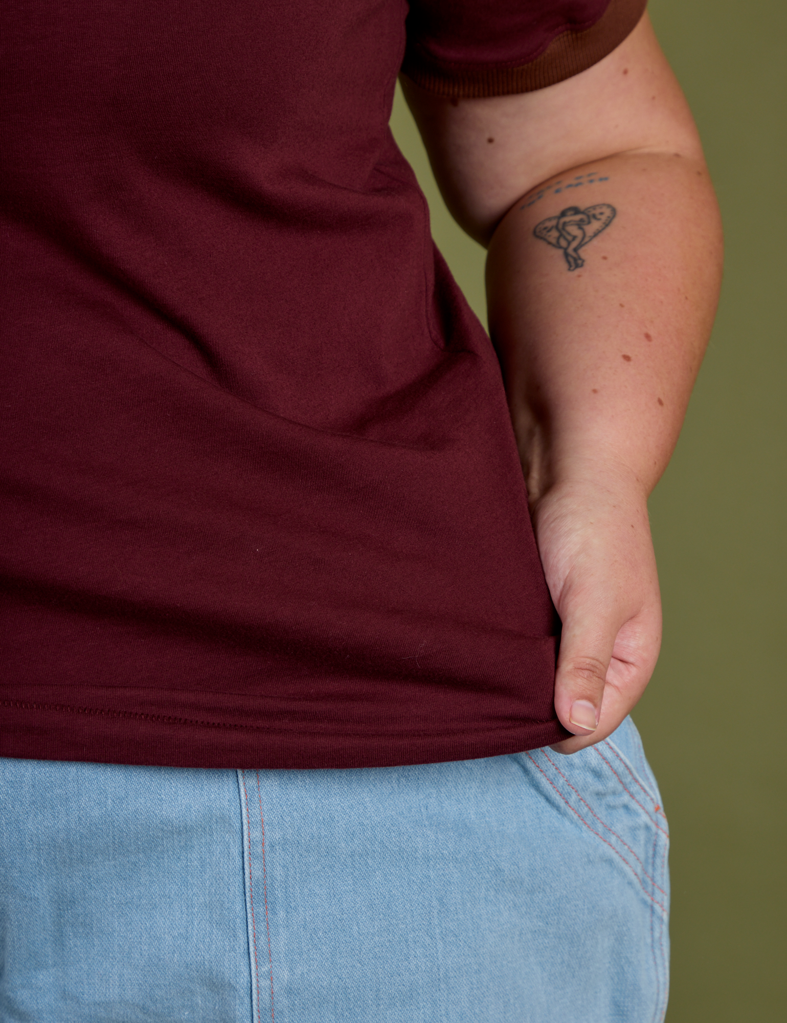 Close up of Juliet holding the bottom hem of Vintage Ringer Tee in Red Wine
