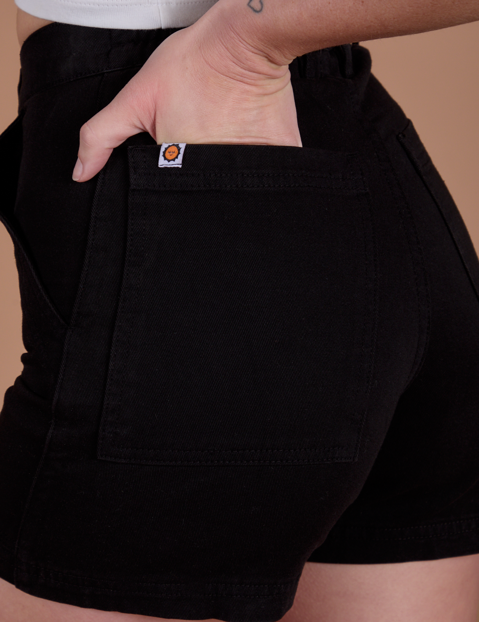 Close up of Alex's hand in the back pocket of Classic Work Shorts in Basic Black