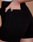 Close up of Alex's hand in the back pocket of Classic Work Shorts in Basic Black