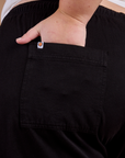 Close up of Juliet's hand in the back pocket of Organic Action Pants in Basic Black