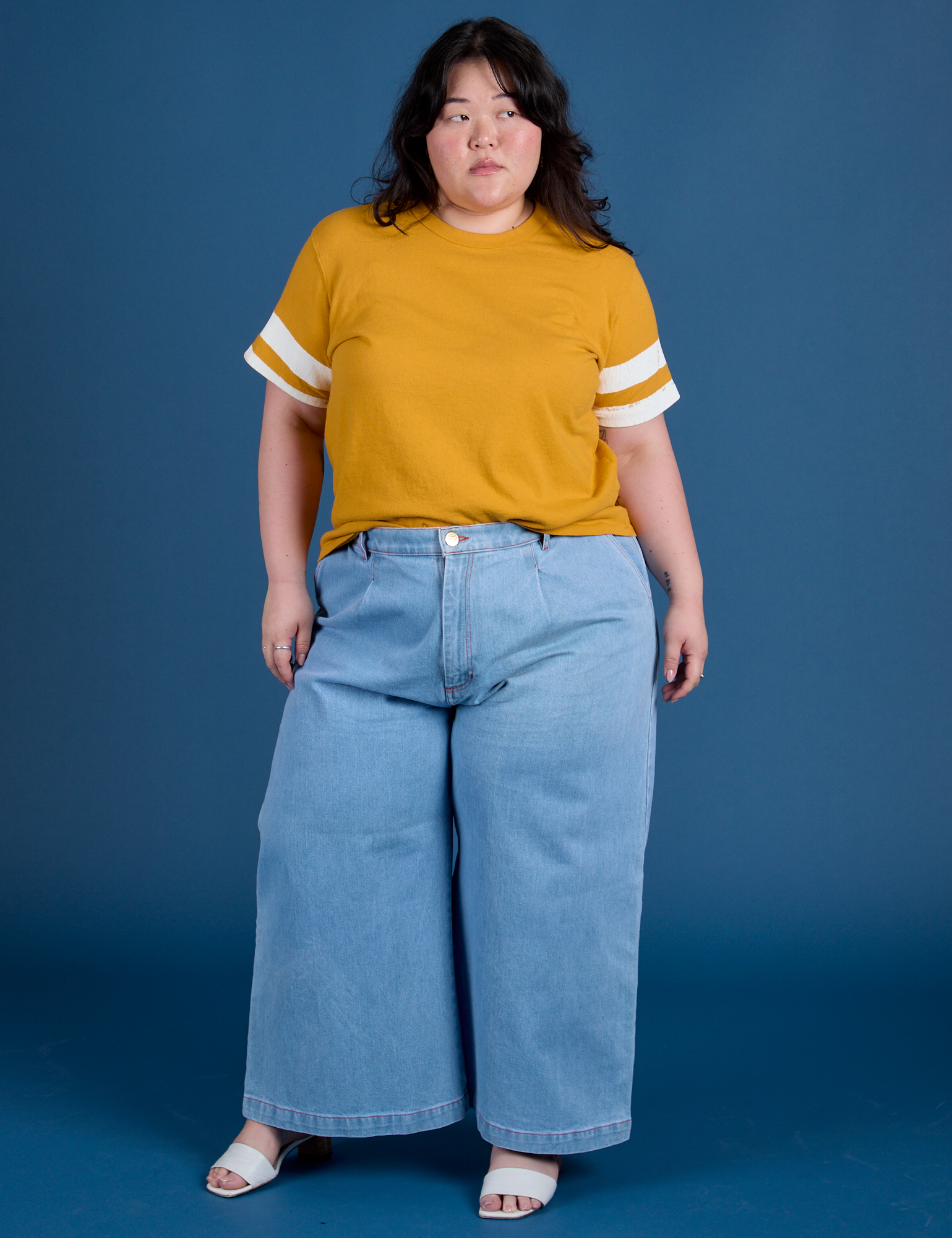 Ashley is wearing Painted Burly Tee in Mustard Yellow and light wash Wide Leg Trousers