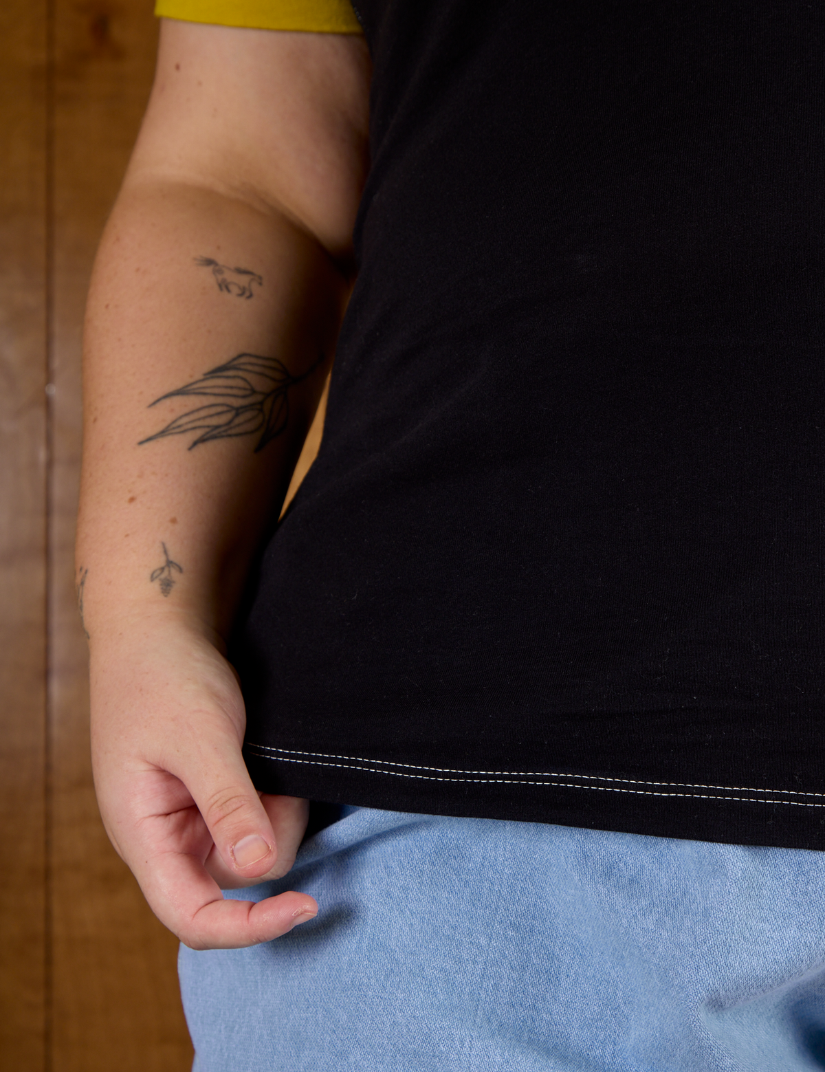 Close up of Juliet holding the bottom hem of Calypso Tee in Black Multi
