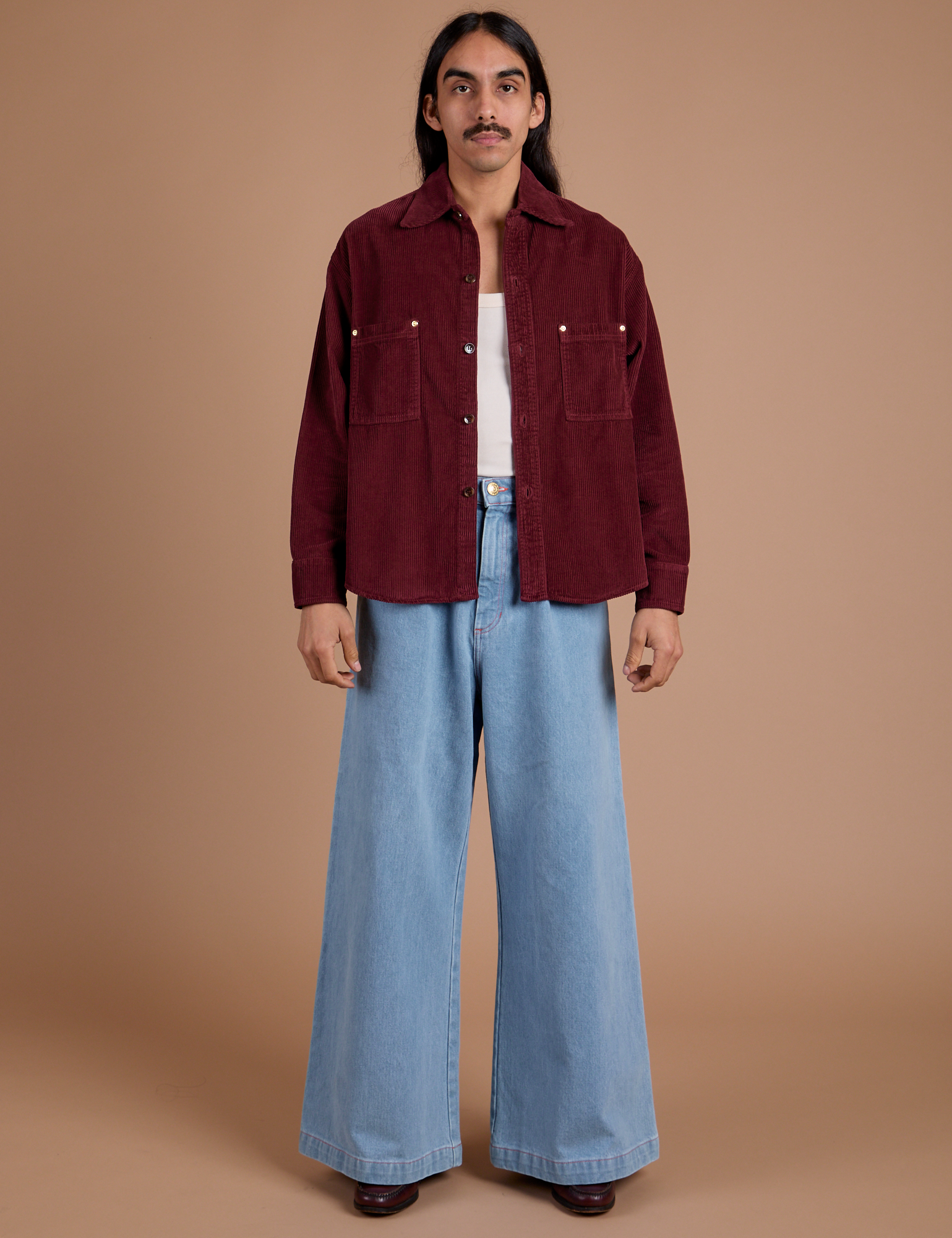 Anthony is wearing Cropped Corduroy Overshirt in Red Wine and light wash Indigo Wide Leg Trousers
