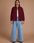 Anthony is wearing Cropped Corduroy Overshirt in Red Wine and light wash Indigo Wide Leg Trousers