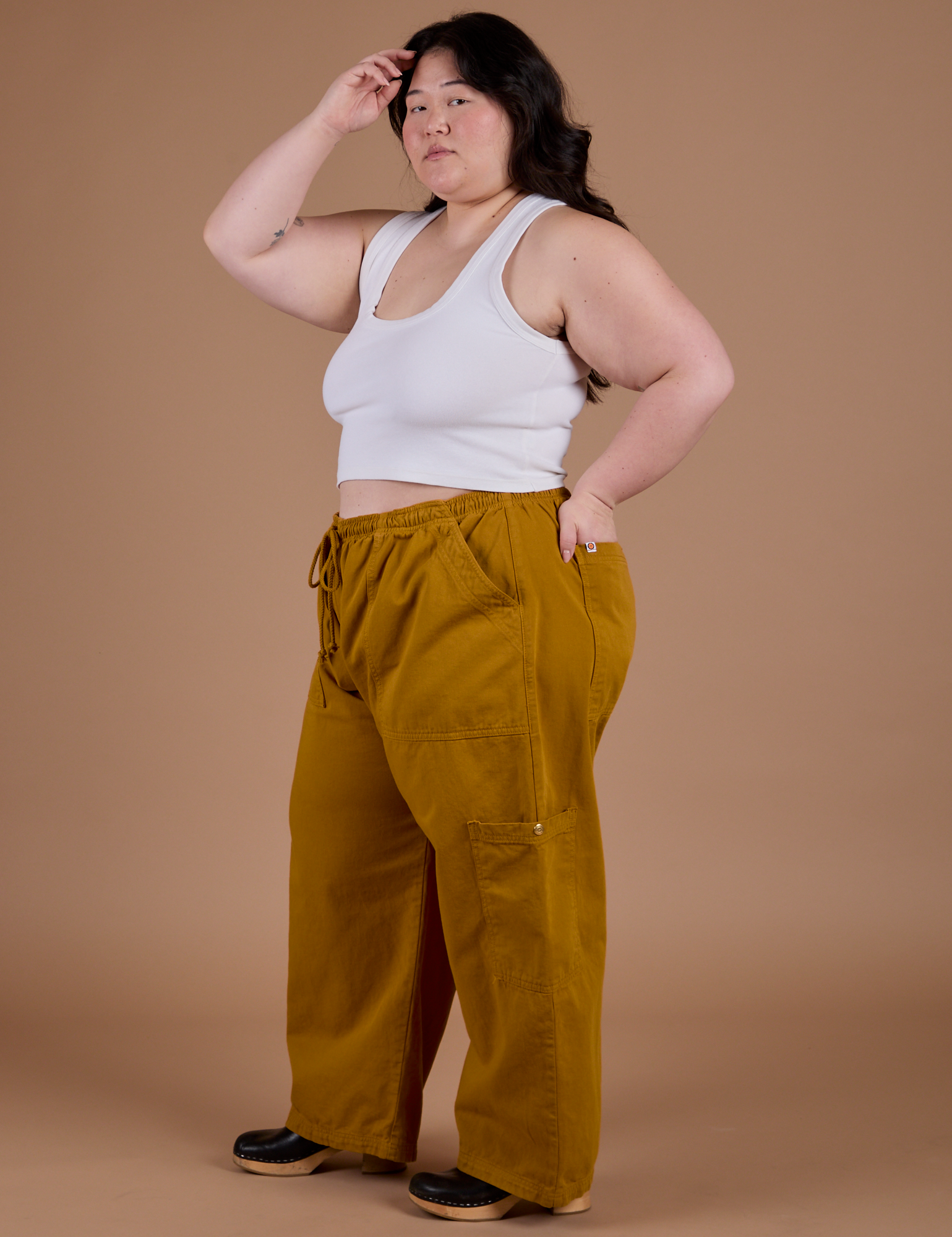 Side view of Drop Pocket Cargo Pants in Spicy Mustard and Cropped Tank in Vintage Tee White on Ashley