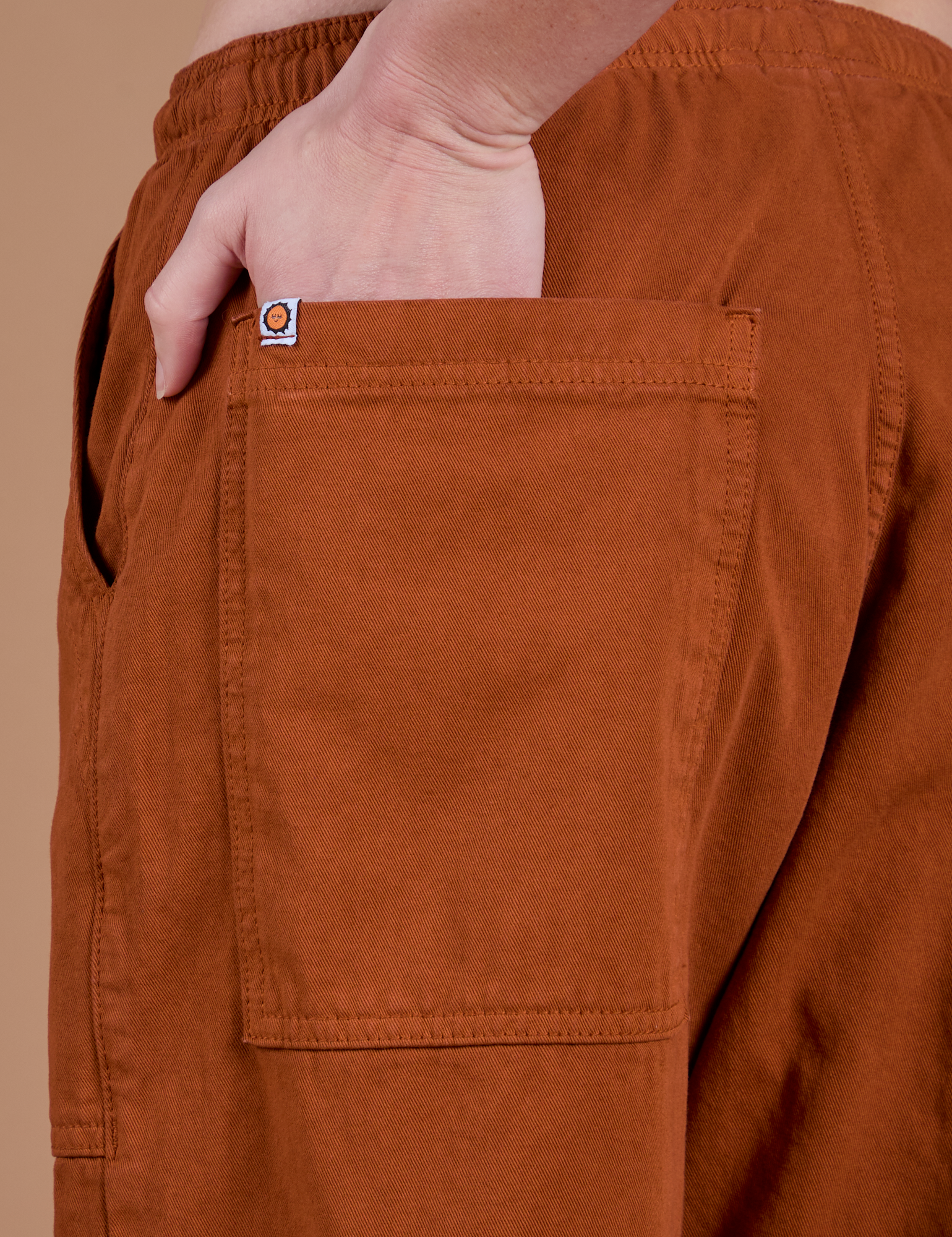 Close up of Alex's hand in the back pocket of Drop Pocket Cargo Pants in Burnt Terracotta