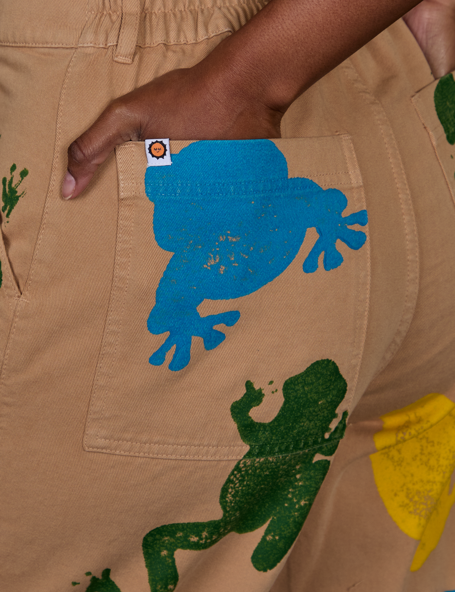 Close up of Kandia's hand in the back pocket of Paintstamped Work Pants in Froggy