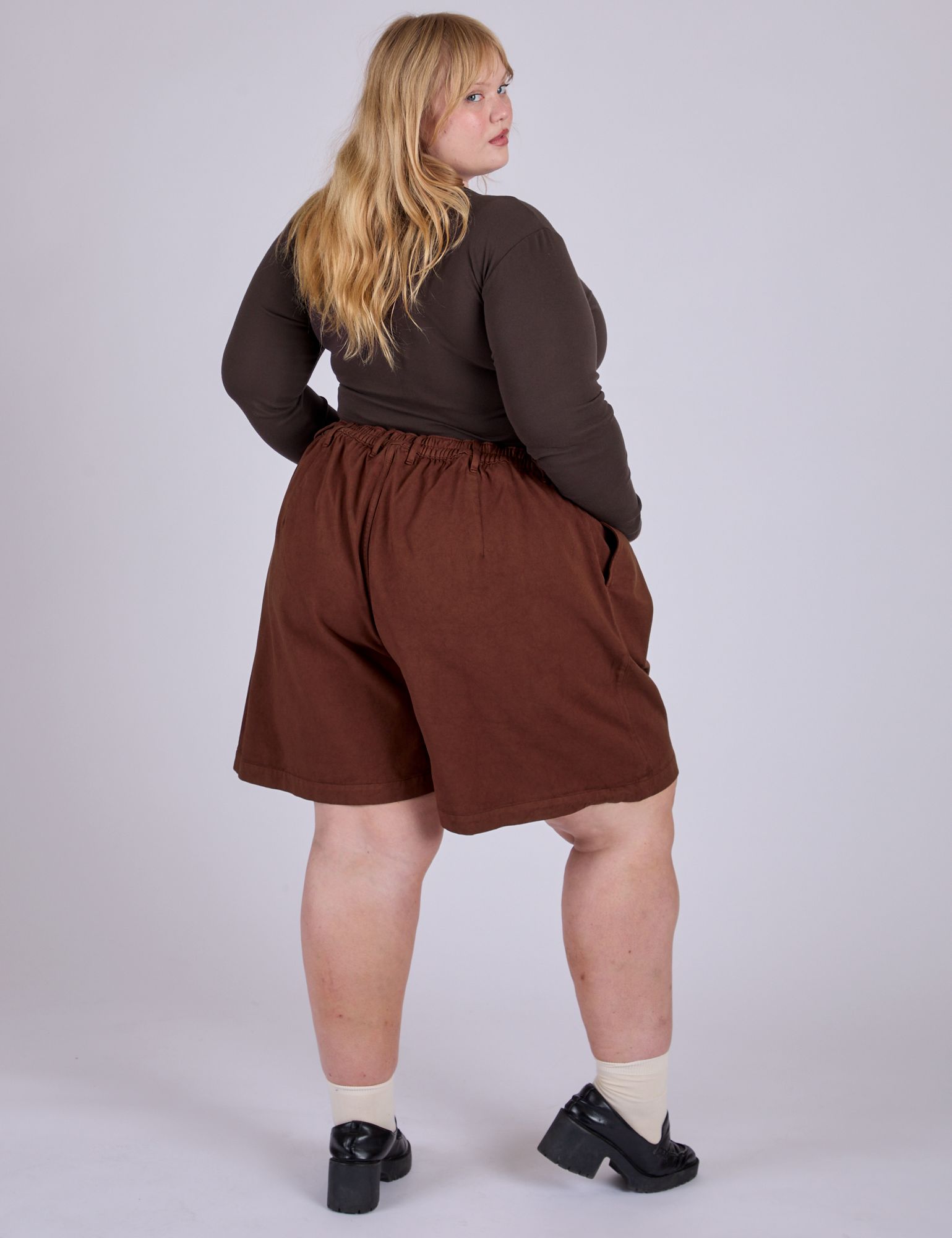 Pleated Trouser Shorts in Fudgesicle Brown angled back view on Juliet