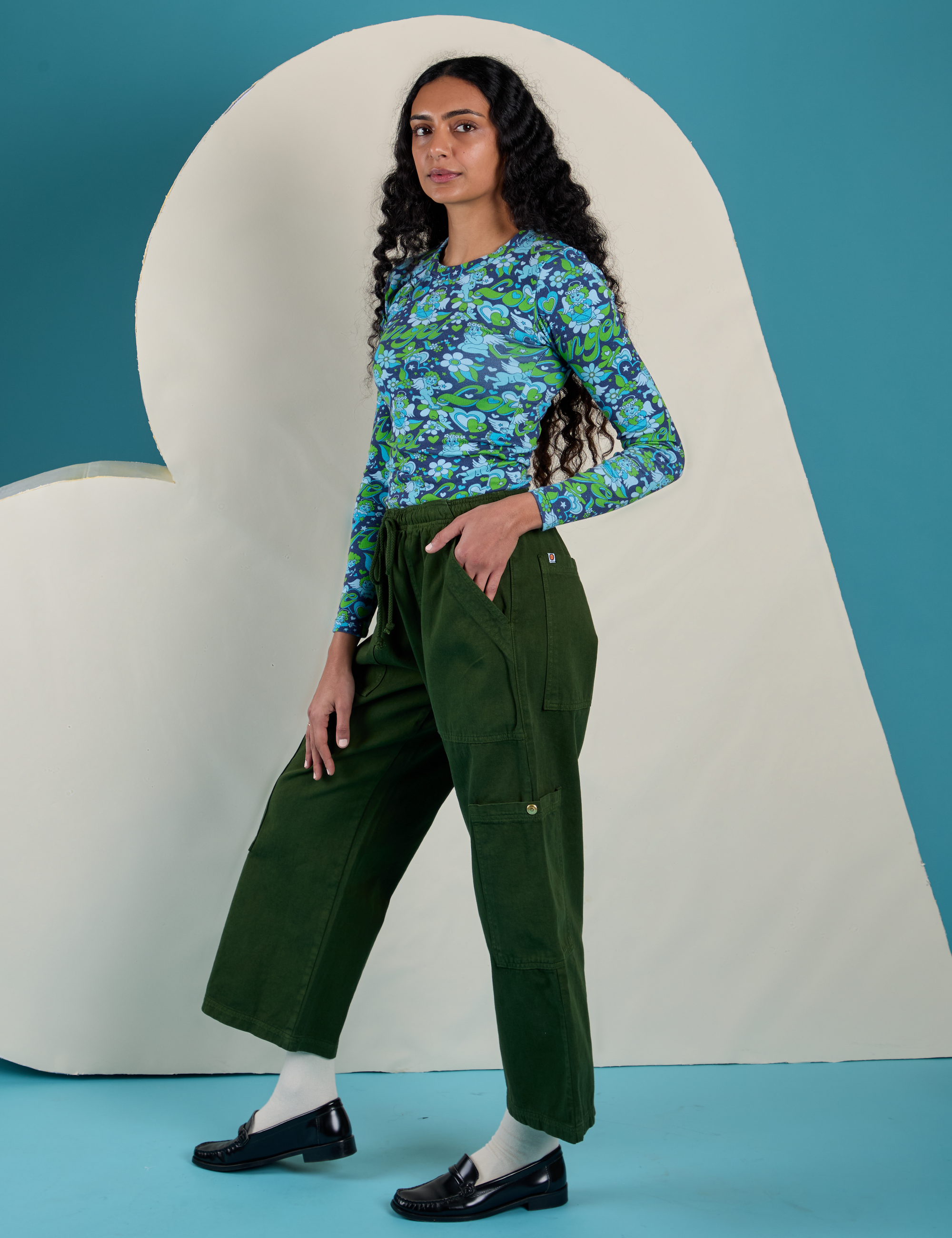 Side view of Long Sleeve Baby Tee in Angel Print and evergreen Drop Pocket Cargo Pants on Shahana
