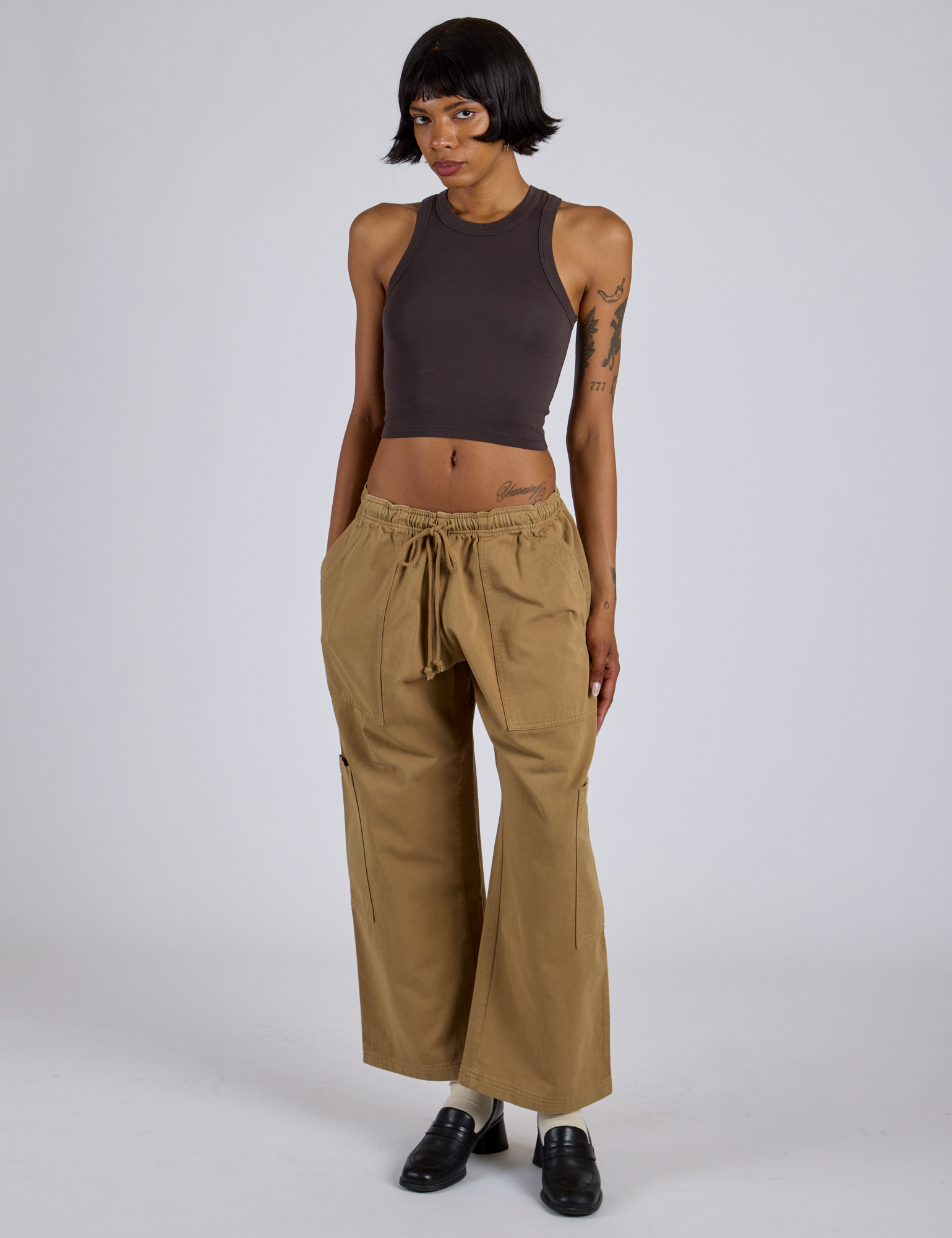 Kira is 5’10” and wearing XS Drop Pocket Cargo Pants in Desert Brown paired with espresso brown Racerback Tank