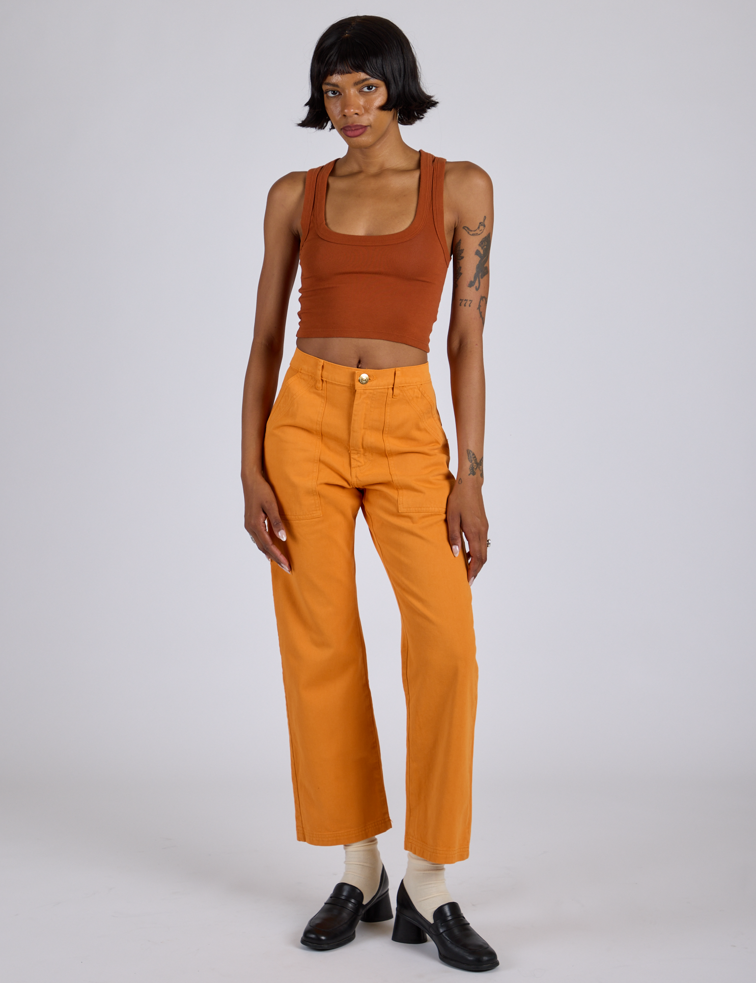 Kira is 5’10” and wearing XS Work Pants in Creamsicle Orange paired burnt terracotta Cropped Tank