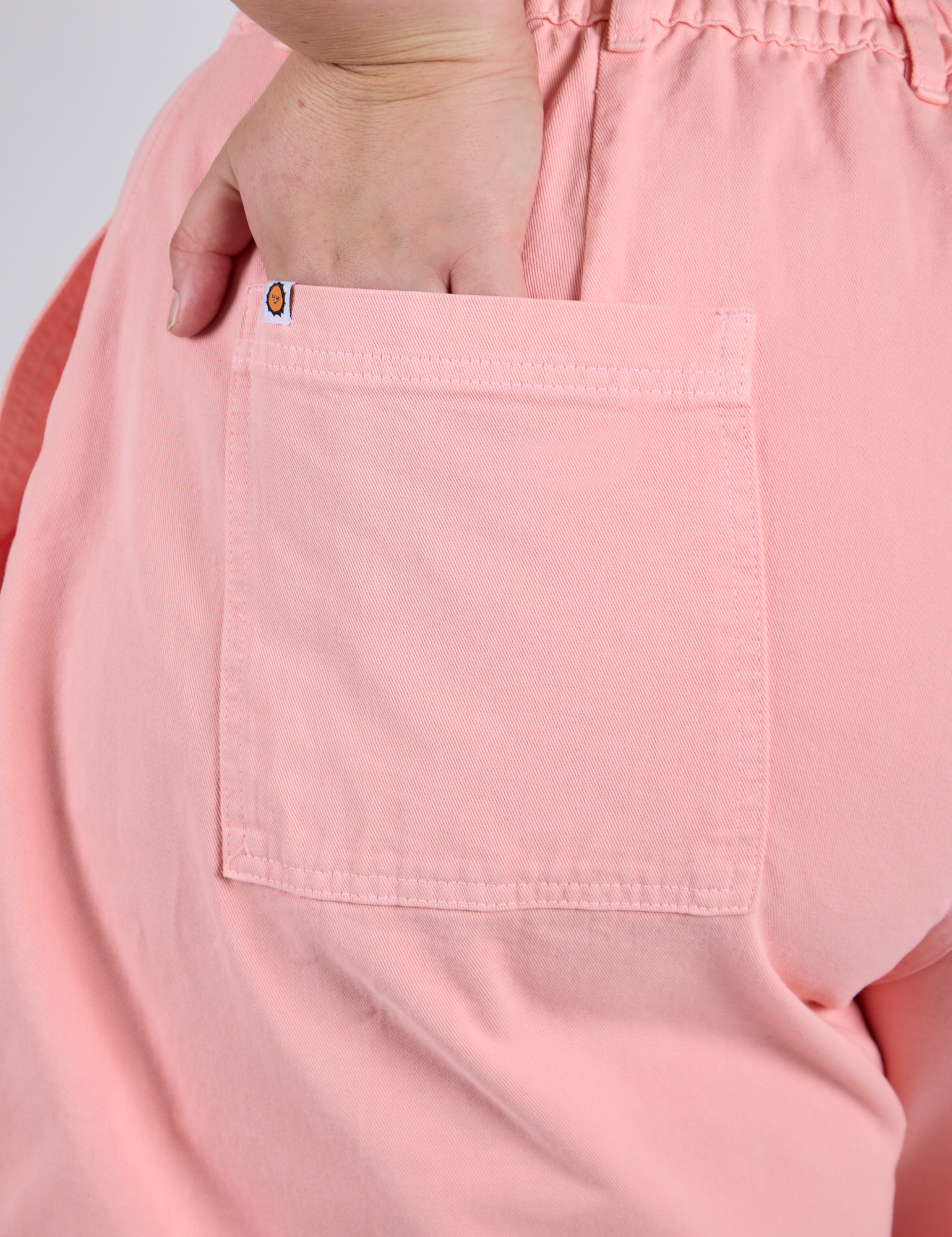 Close up of Juliet's hand in the back pocket of Longline Work Shorts in Baby Pink