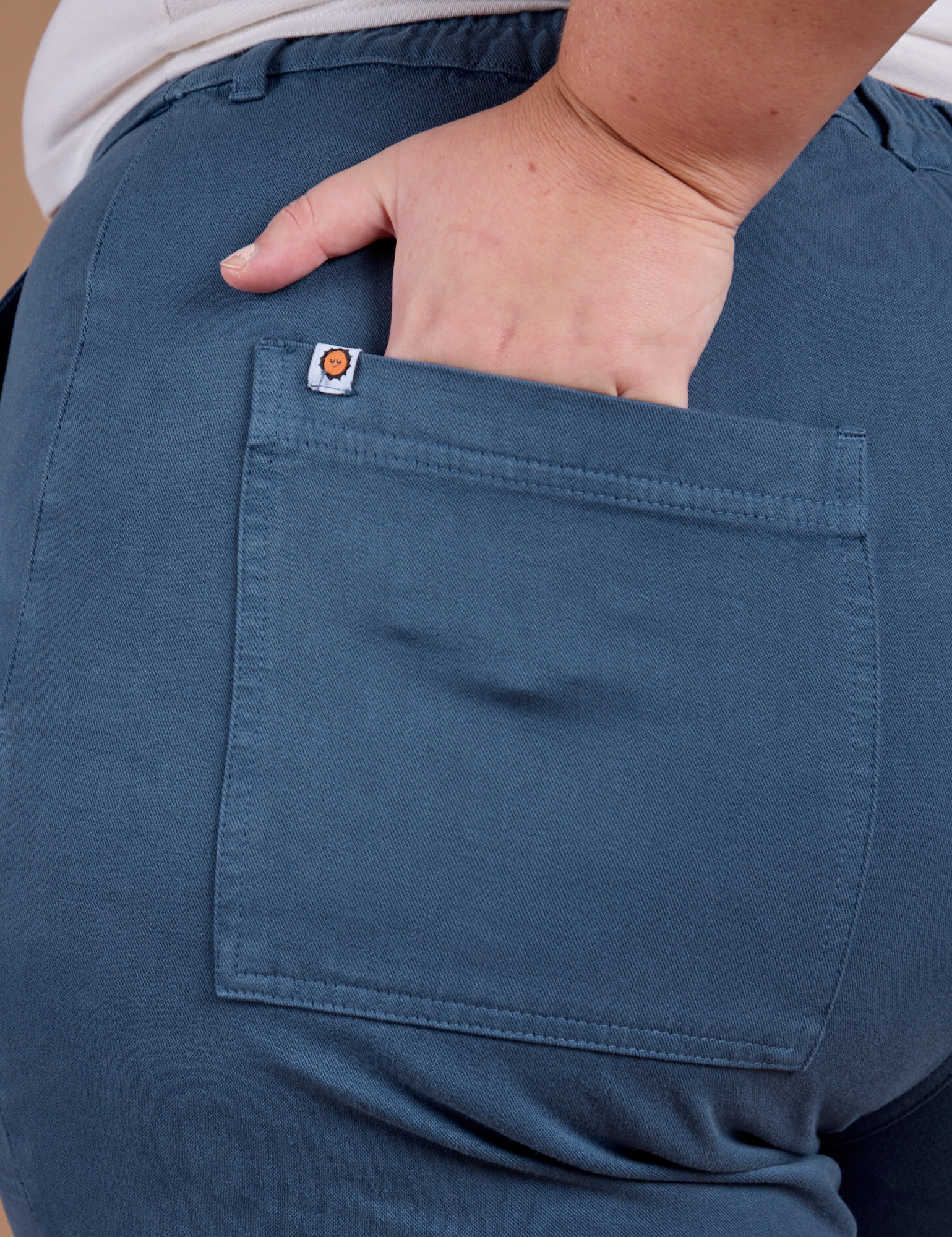 Close up of Juliet's hand in the back pocket of Organic Work Pants in French Blue