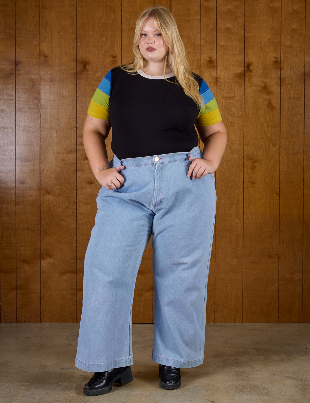Juliet is wearing Calypso Tee in Black Multi tucked into light wash denim wide leg trousers