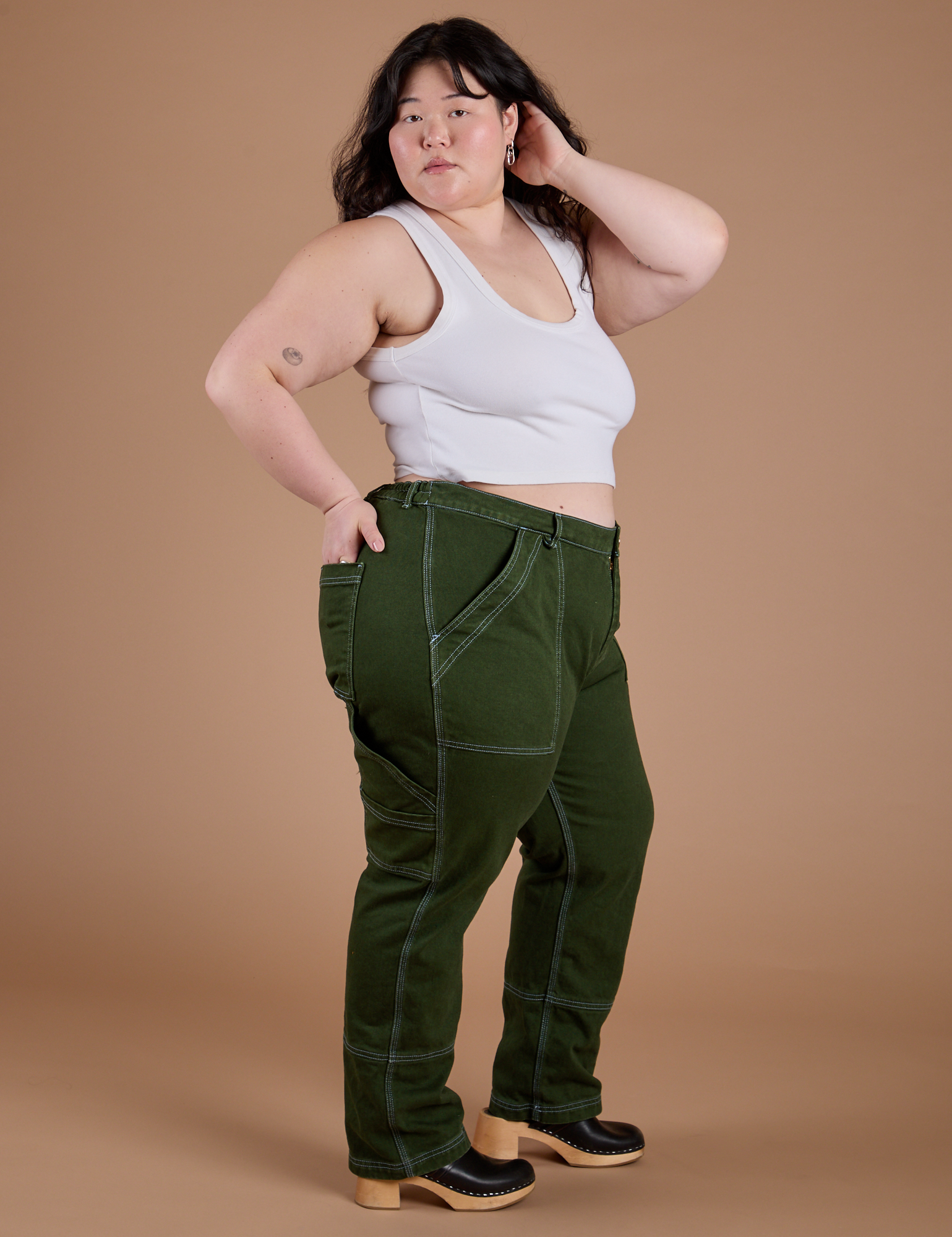 Side view of Carpenter Jeans in Evergreen and vintage tee white Cropped Tank on Ashley