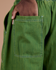 Close up of Isaac's hand in the back pocket of Denim Drop Pocket Pants in Green Overdye