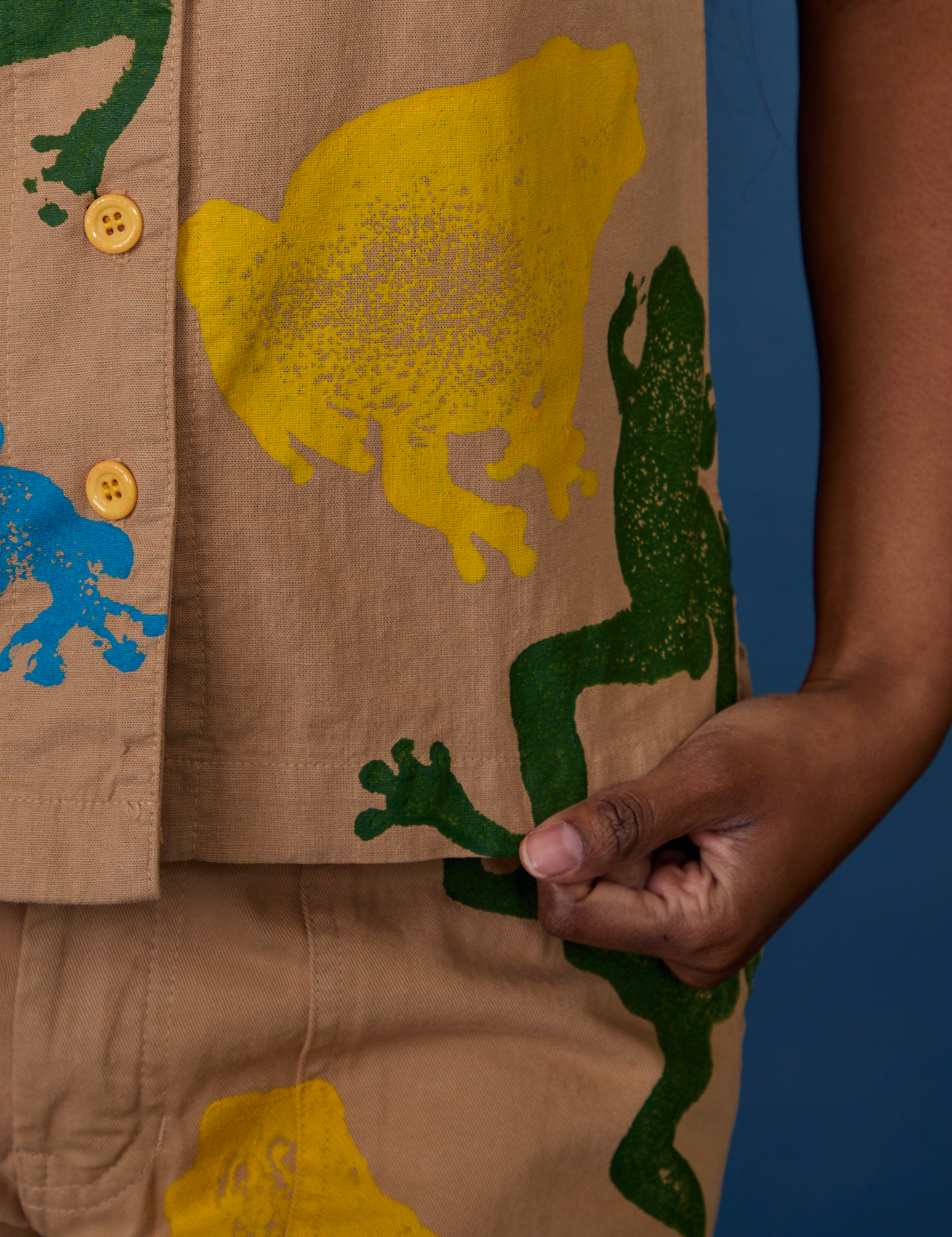 Close up of Kandia holding the bottom hem of Paintstamped Pantry Button-Up in Froggy