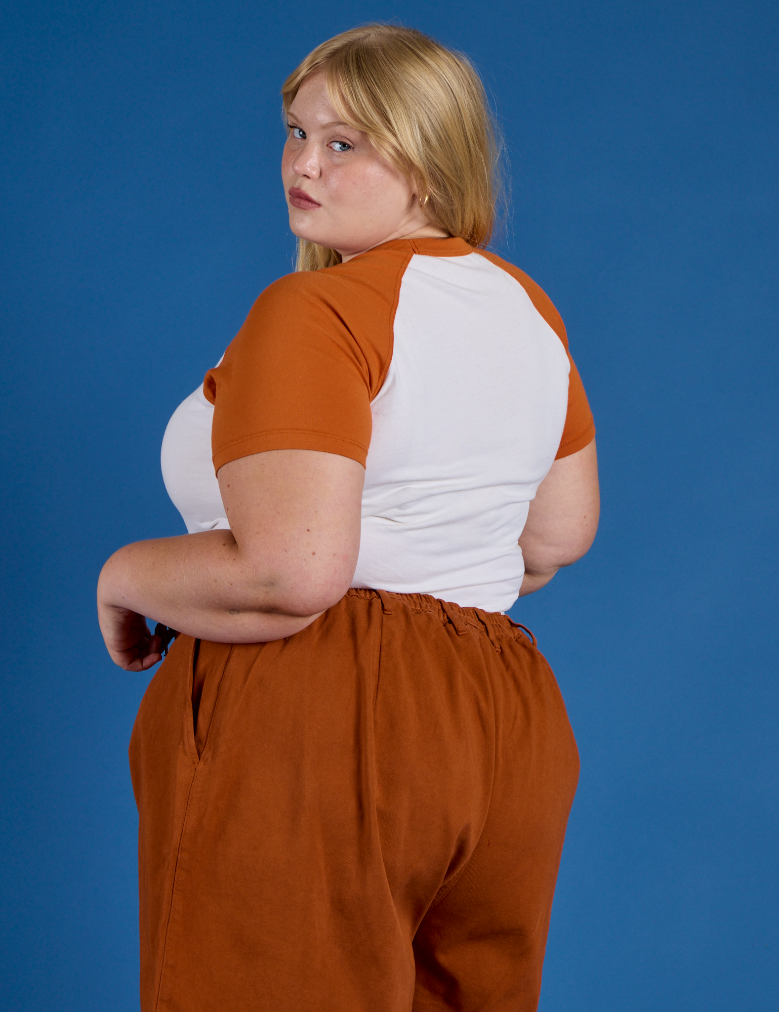 Angled back view of Produce Raglan Tee in Orange on Juliet