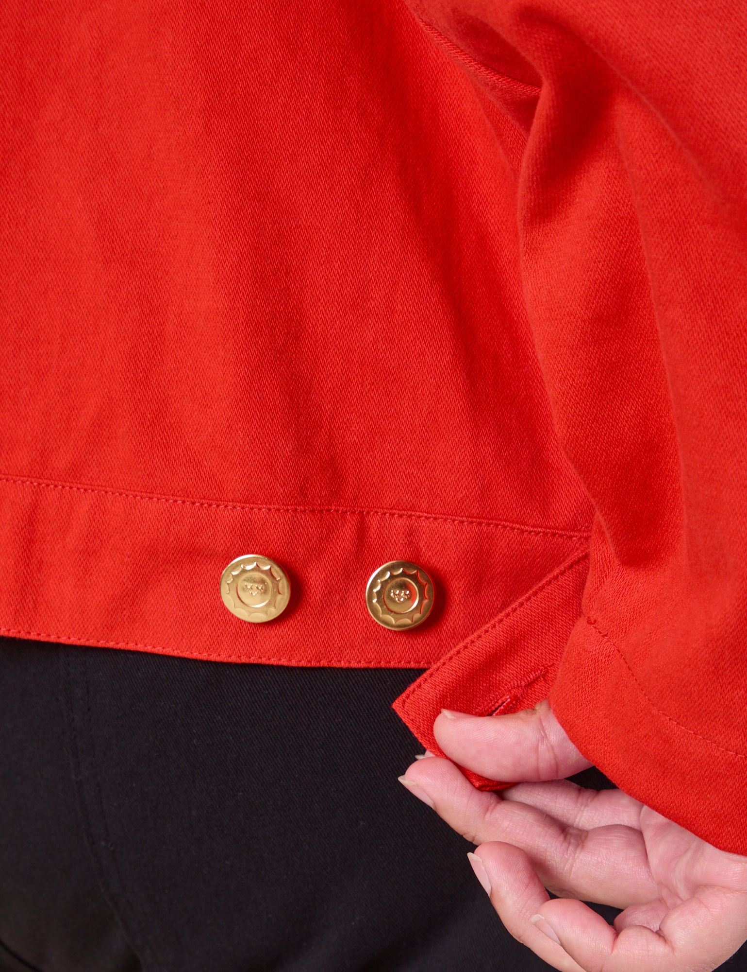 Close up of custom brass buttons on the Mechanic Jacket in Mustang Red worn by Miguel