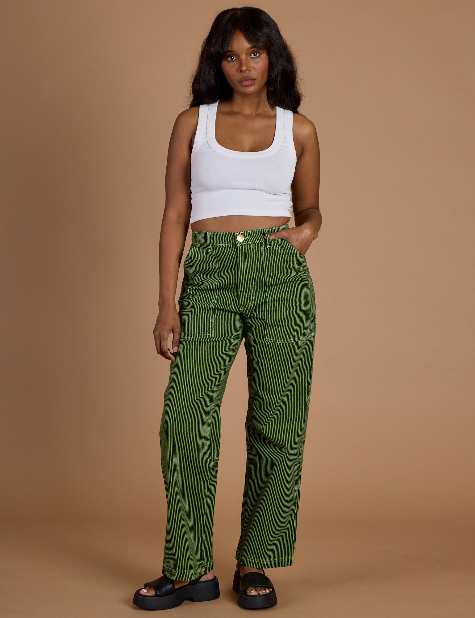 Kandia is 5’3” and wearing XS Railroad Denim Work Pants in Gross Green Overdye paired with vintage tee white Cropped Tank