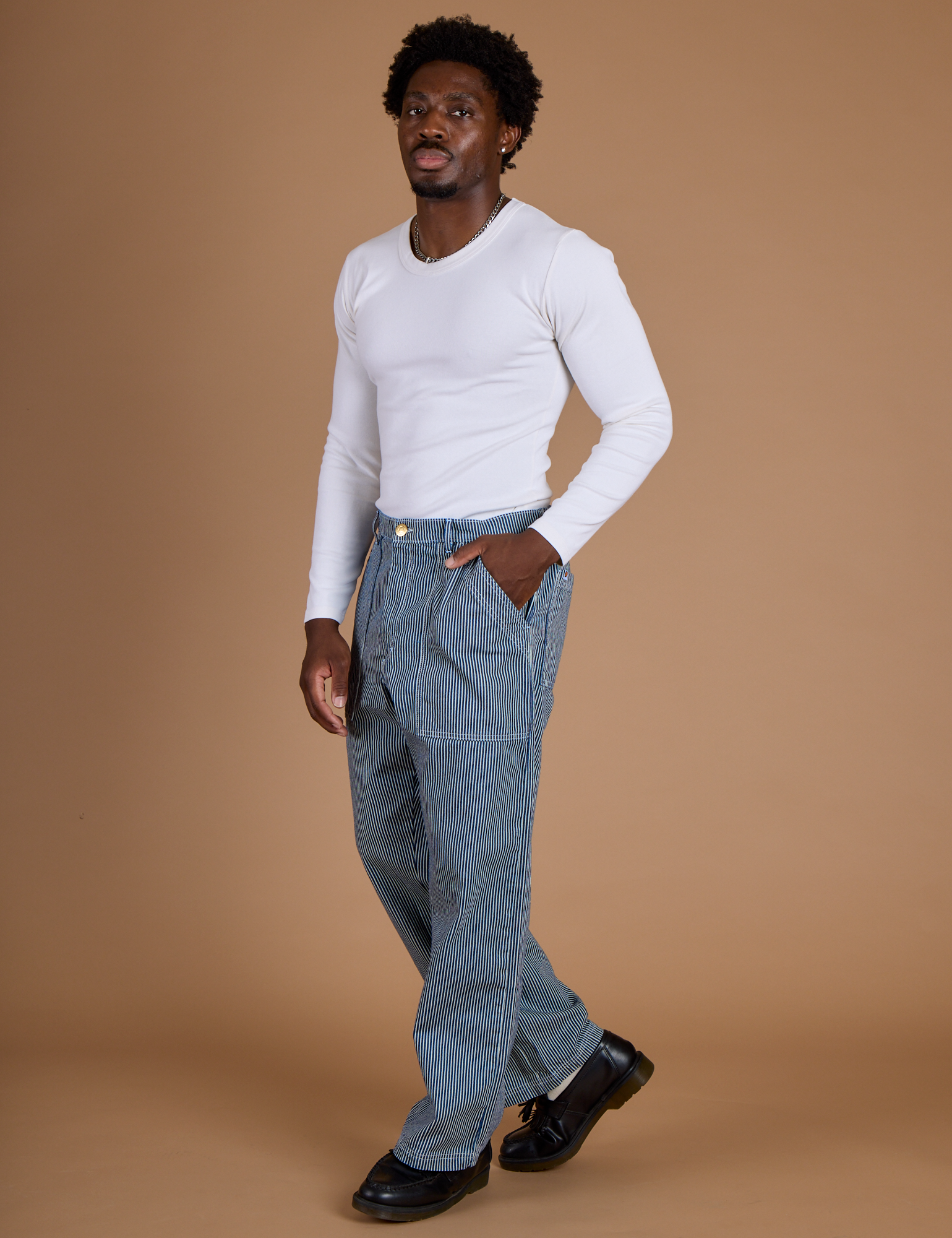 Angled front view of Railroad Denim Work Pants in Natural and vintage tee white Long Sleeve Baby Tee