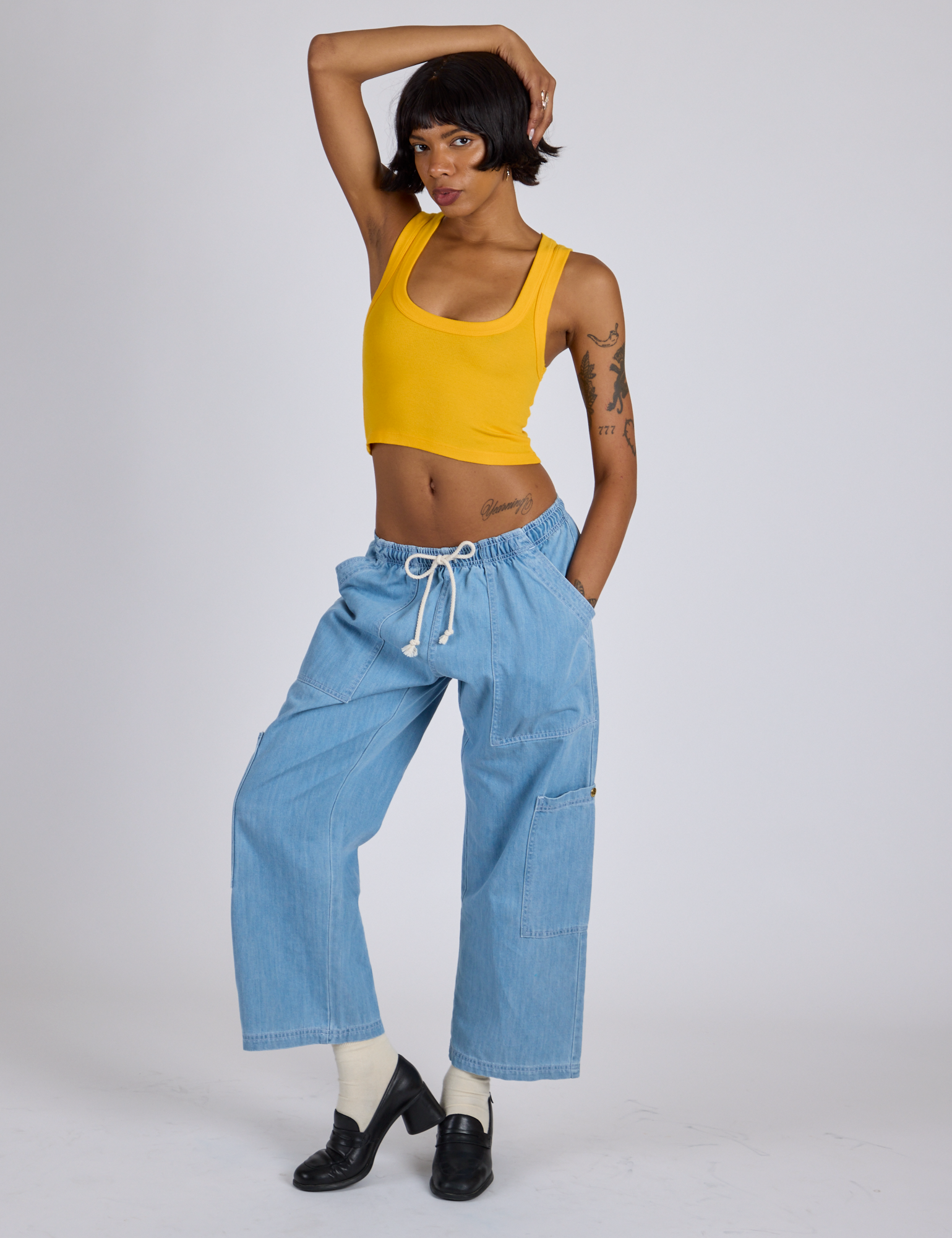 Kira is wearing Cropped Tank Top in Sunshine Yellow and light wash Denim Drop Pocket Pants