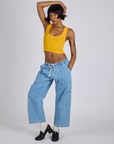 Kira is wearing Cropped Tank Top in Sunshine Yellow and light wash Denim Drop Pocket Pants