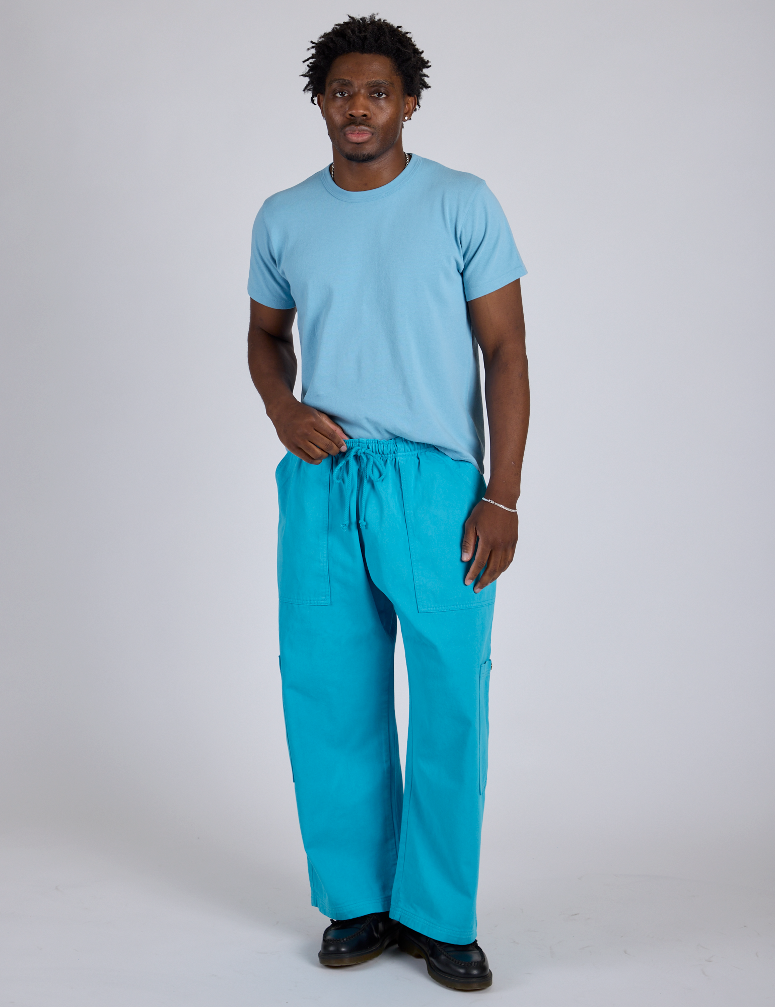 saac is 5’10” and wearing M Drop Pocket Cargo Pants in Hawaiian Blue paired with a baby blue Organic Vintage Tee
