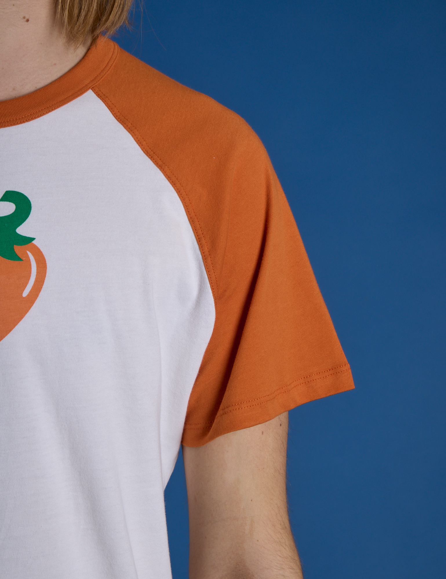 Close up of Produce Raglan Tee in Habanero sleeve on Grant