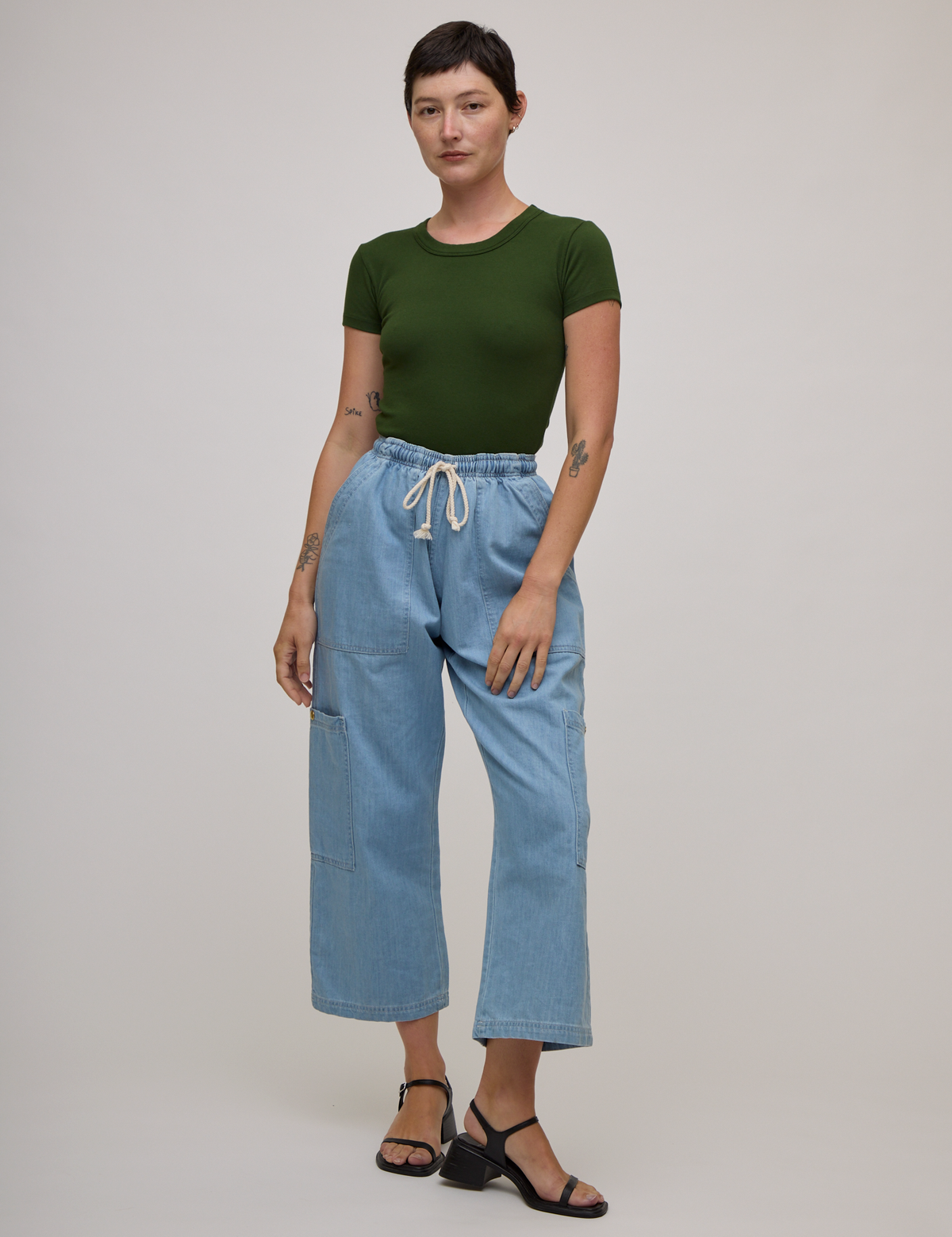 Alex is wearing Baby Tee in Evergreen tucked into light wash denim drop pocket pants