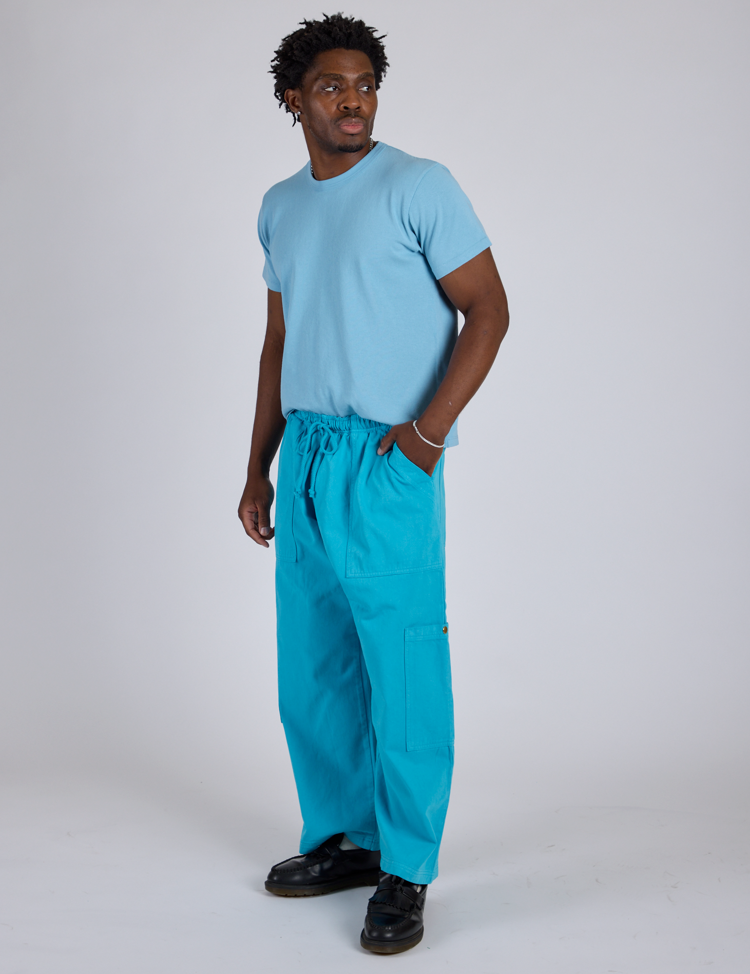 Angled front view of Drop Pocket Cargo Pants in Hawaiian Blue and baby blue Organic Vintage Tee on Isaac
