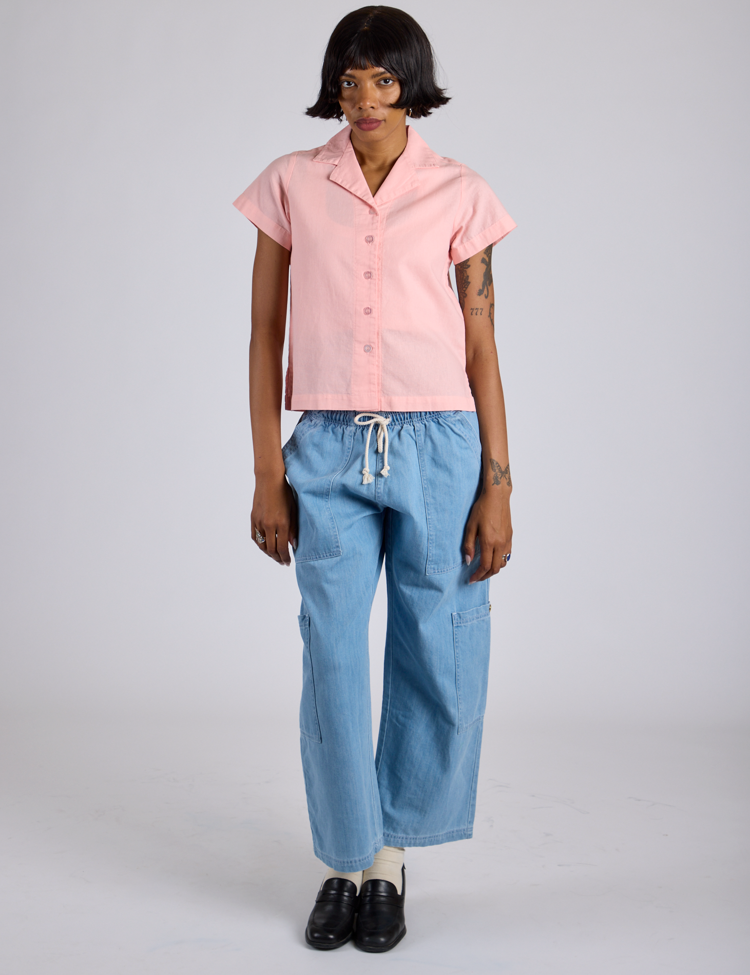 Kira is 5’10” and wearing P Pantry Button-Up in Baby Pink paired with light wash Denim Drop Pocket Pants