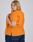 Angled back view of Pantry Button-Up in Creamsicle Orange on Juliet