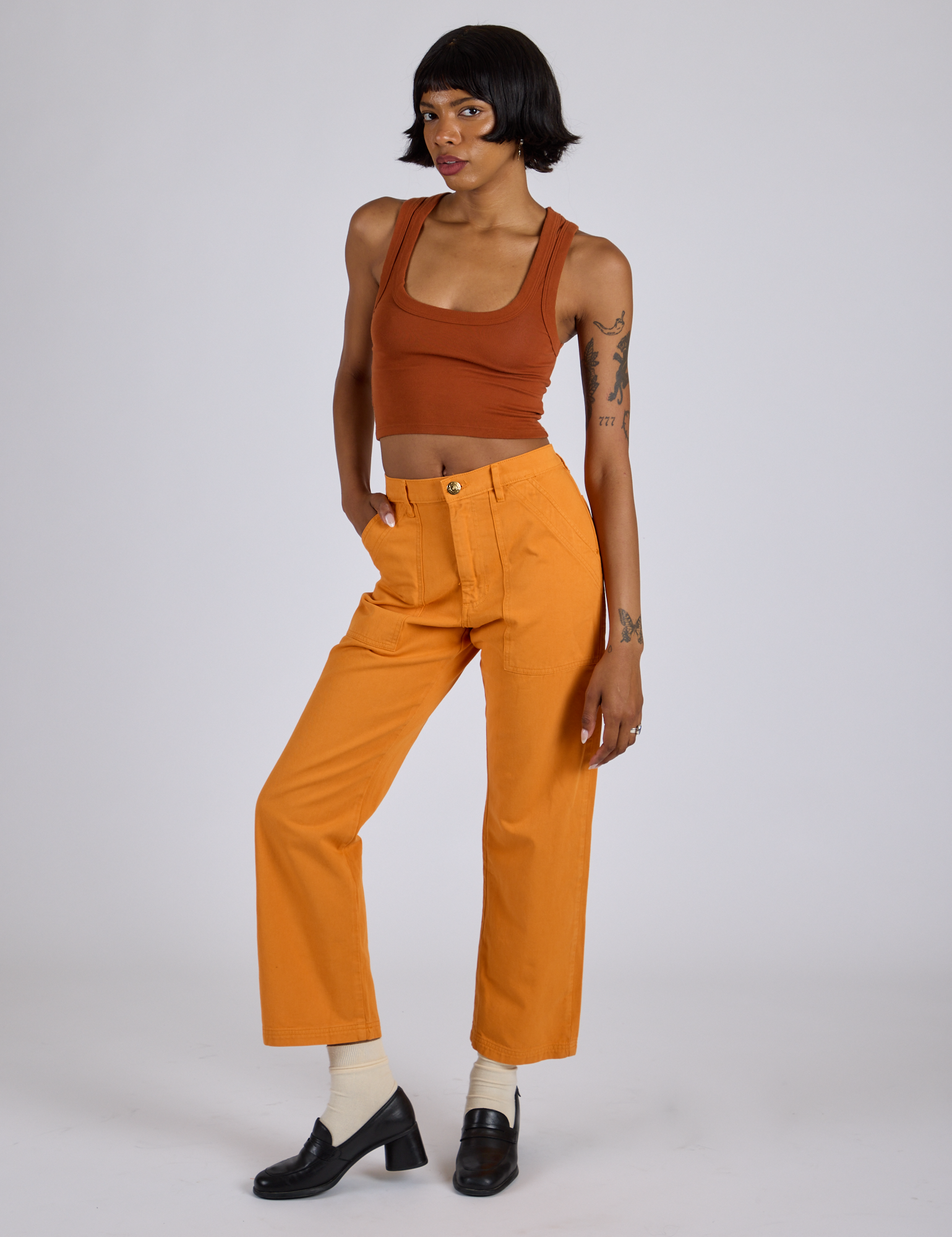 Angled front view of Work Pants in Creamsicle Orange and burnt terracotta Cropped Tank on Kira