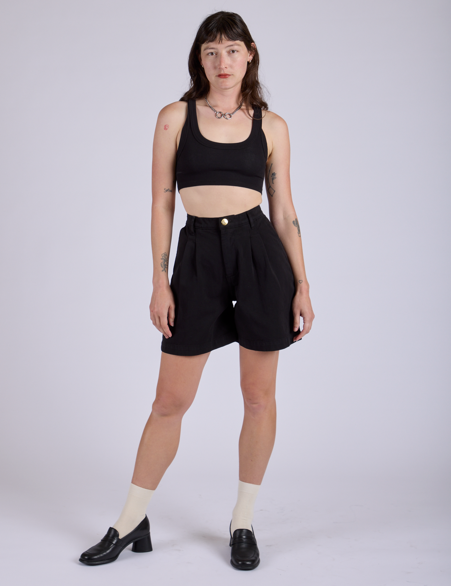 Alex is 5’8” and wearing XXS Pleated Trouser Shorts in Basic Black paired with black Mini Tank