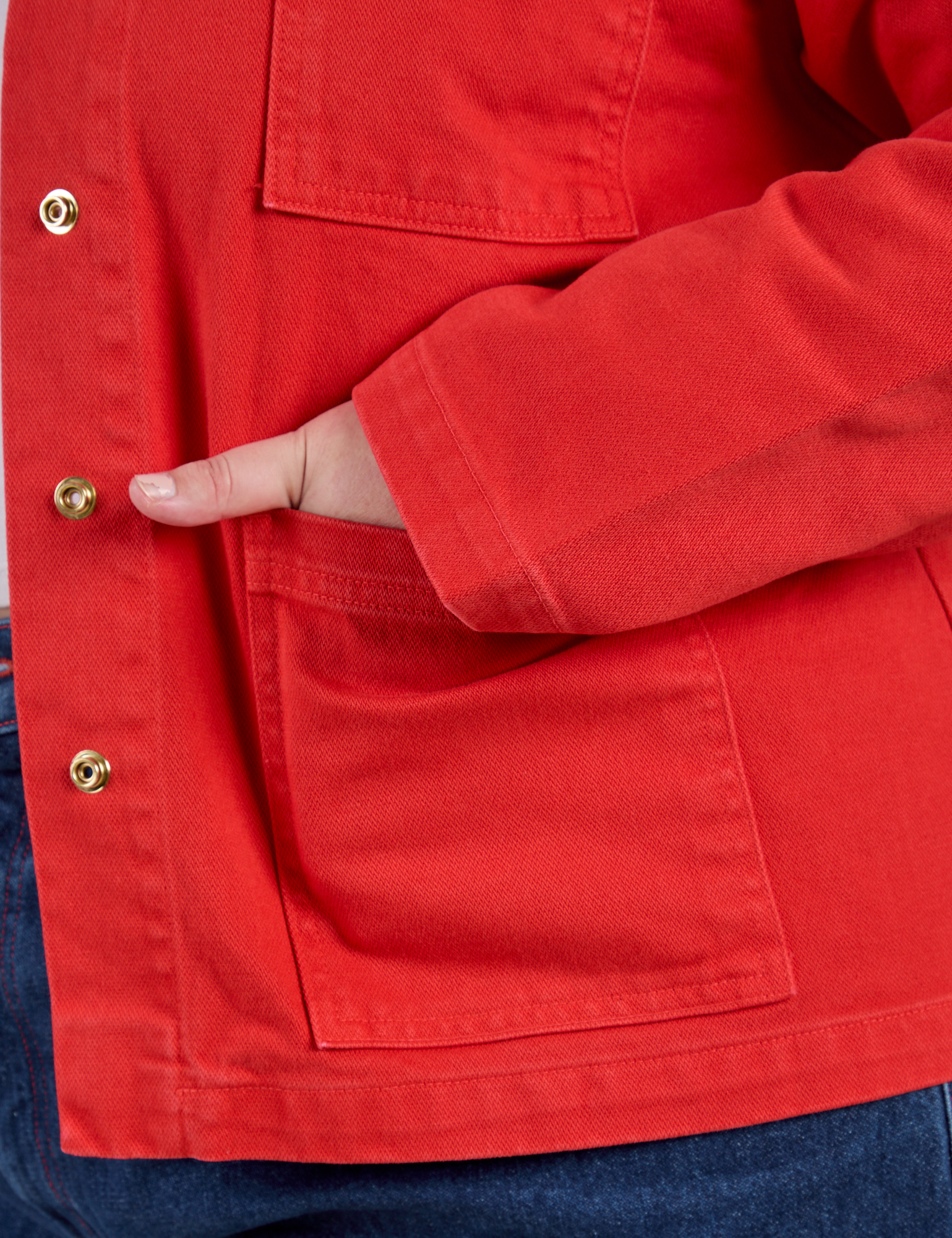 Close up of Juliet's hand in the front pocket of Denim Work Jacket in Mustang Red