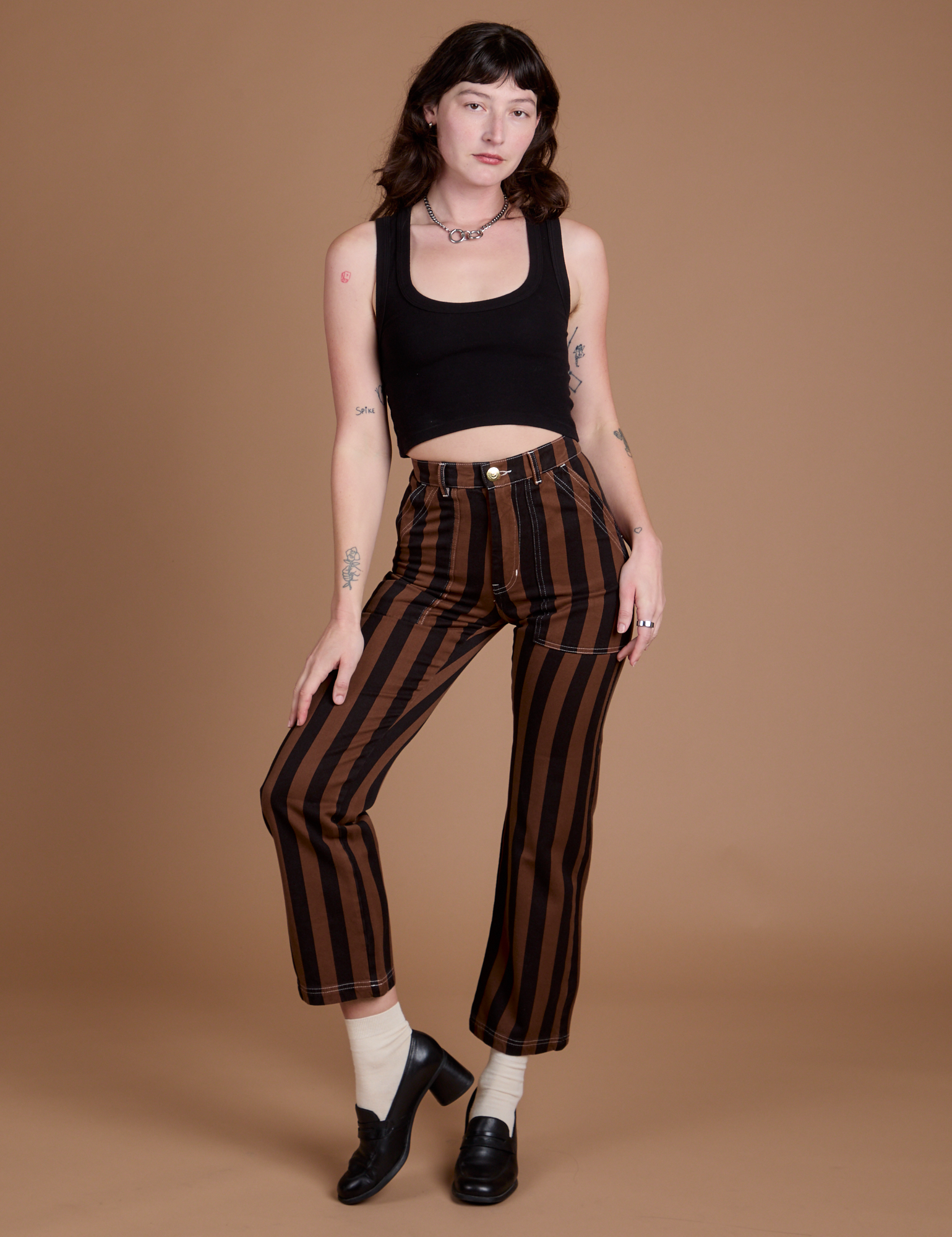 Alex is wearing Black Stripe Work Pants in Fudgesicle Brown and black Cropped Tank