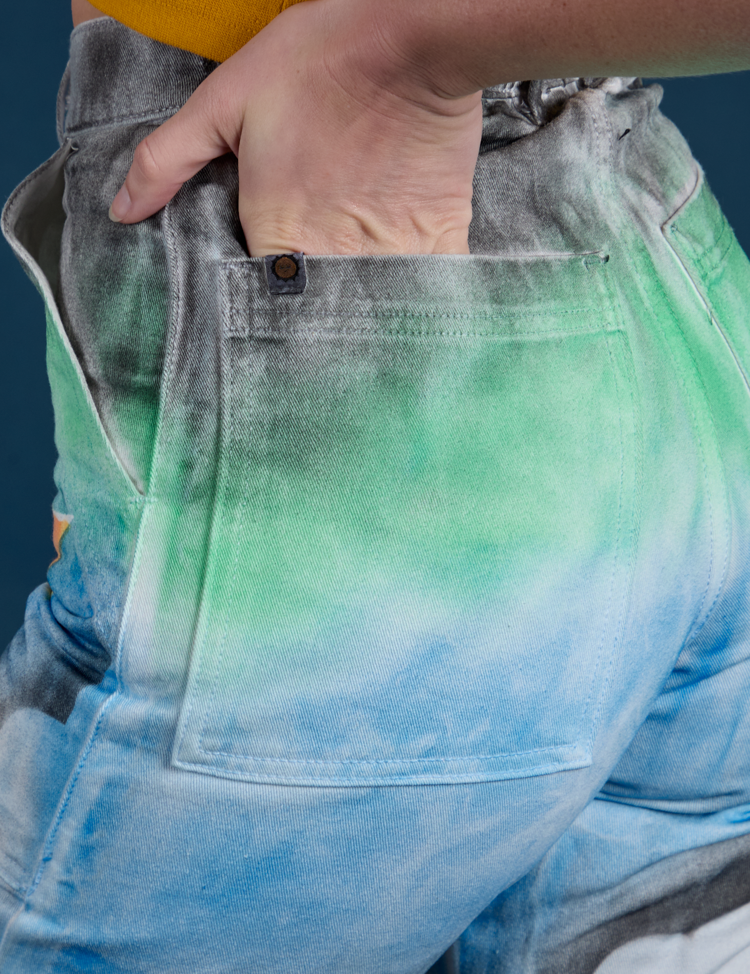 Close up of Alex's hand in the back pocket of Work Pants in Night Sky Airbrush