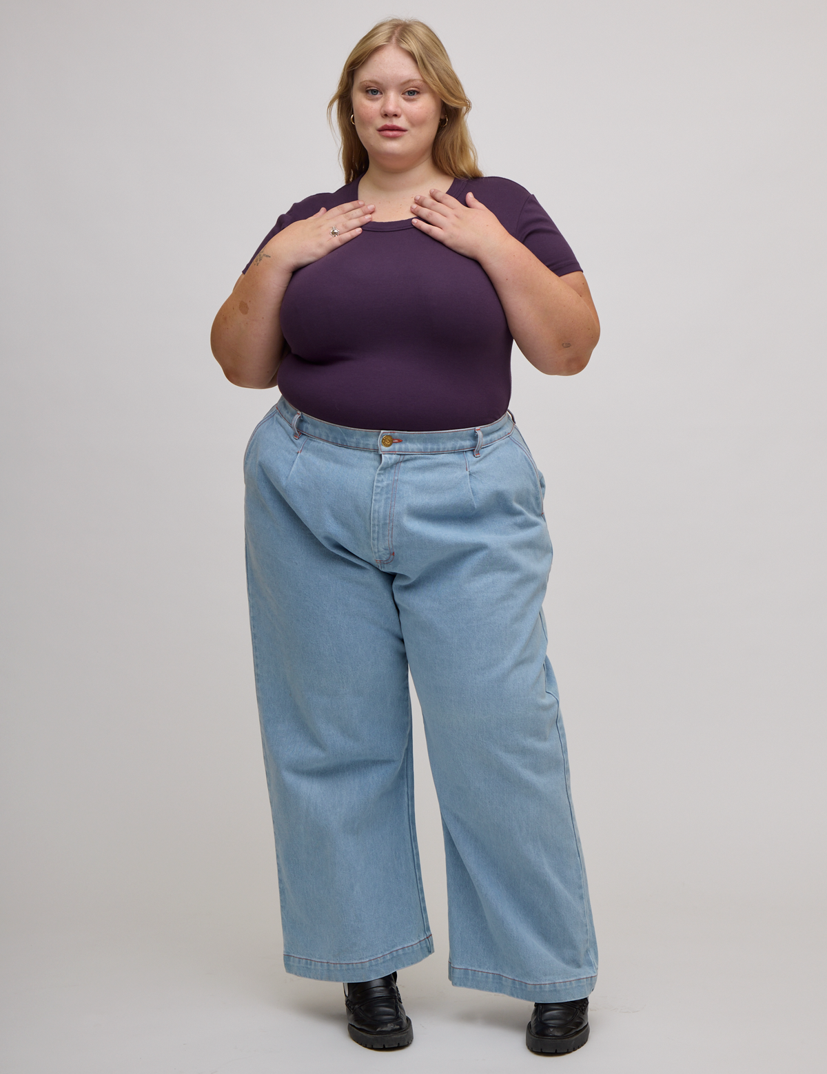 Juliet is wearing Baby Tee in Nebula Purple tucked into light wash wide leg trousers