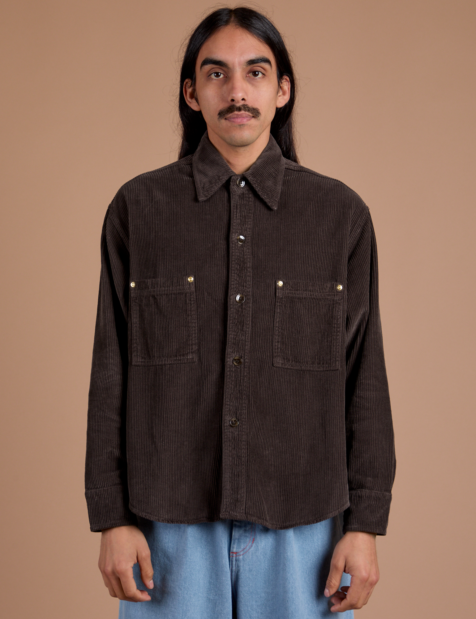 Anthony is wearing a buttoned up Cropped Corduroy Overshirt in Espresso Brown